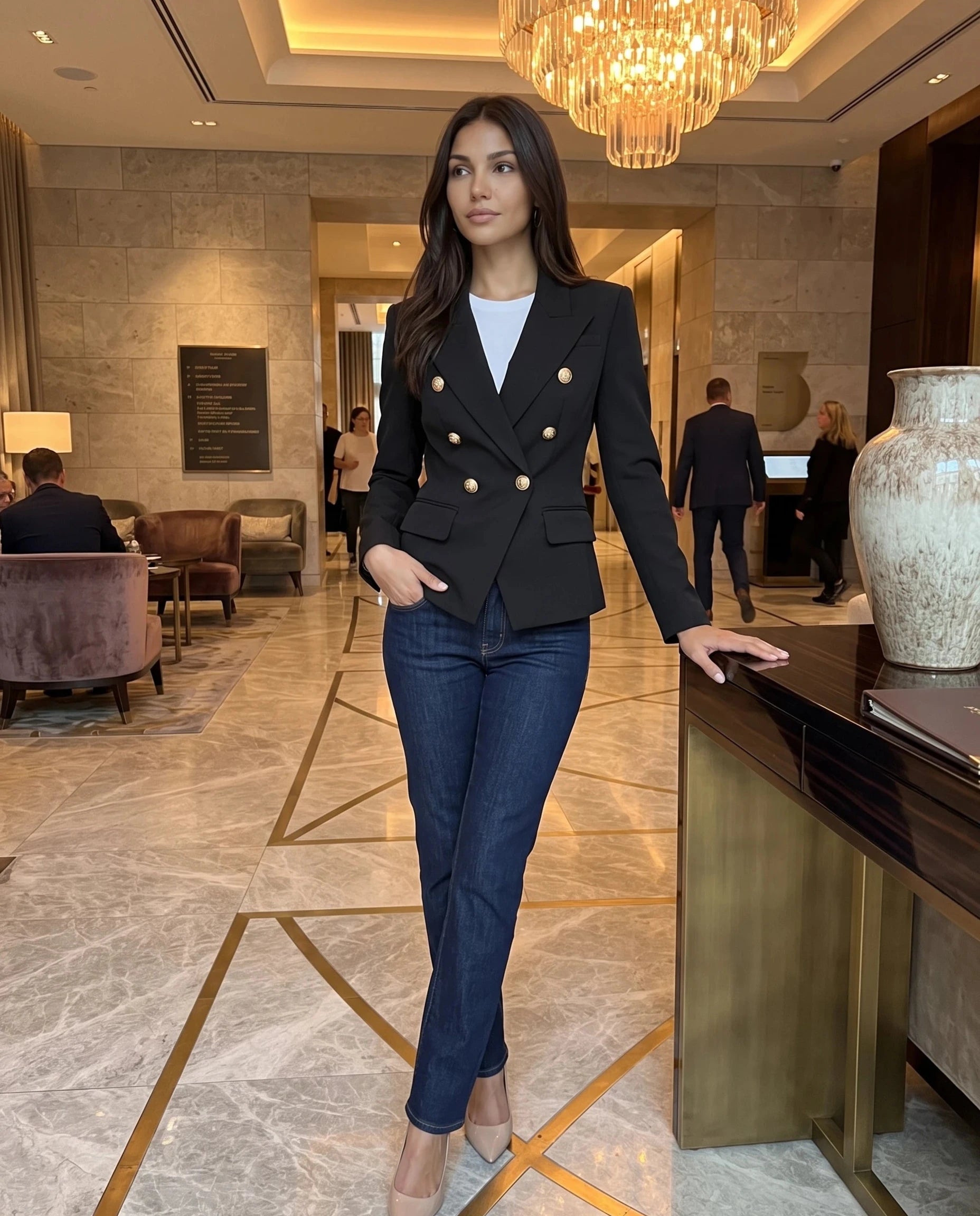 Blazer noir à boutons lion Thaïs, porté dans un hall d'hôtel en marbre