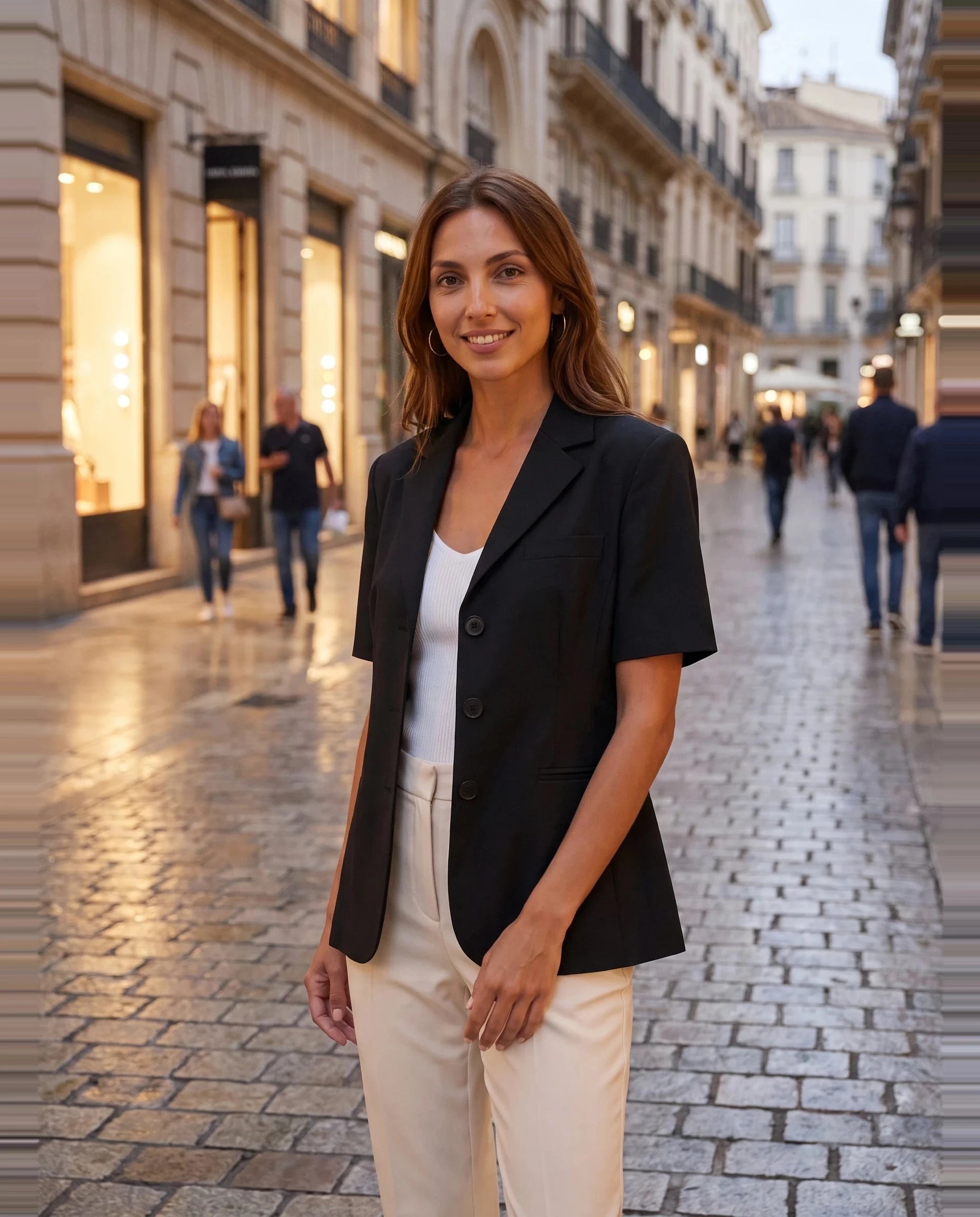 Blazer noir cintré Yolande, porté dans une rue piétonne en début de soirée