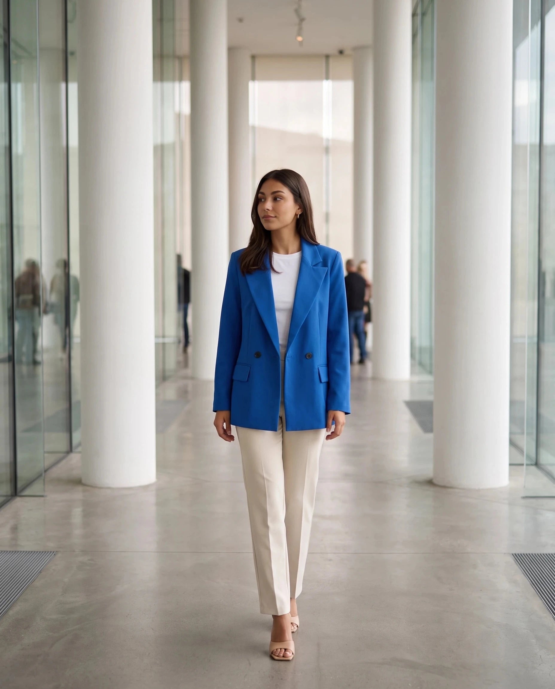 Blazer bleu roi Cosima, porté dans un hall de musée contemporain à colonnes