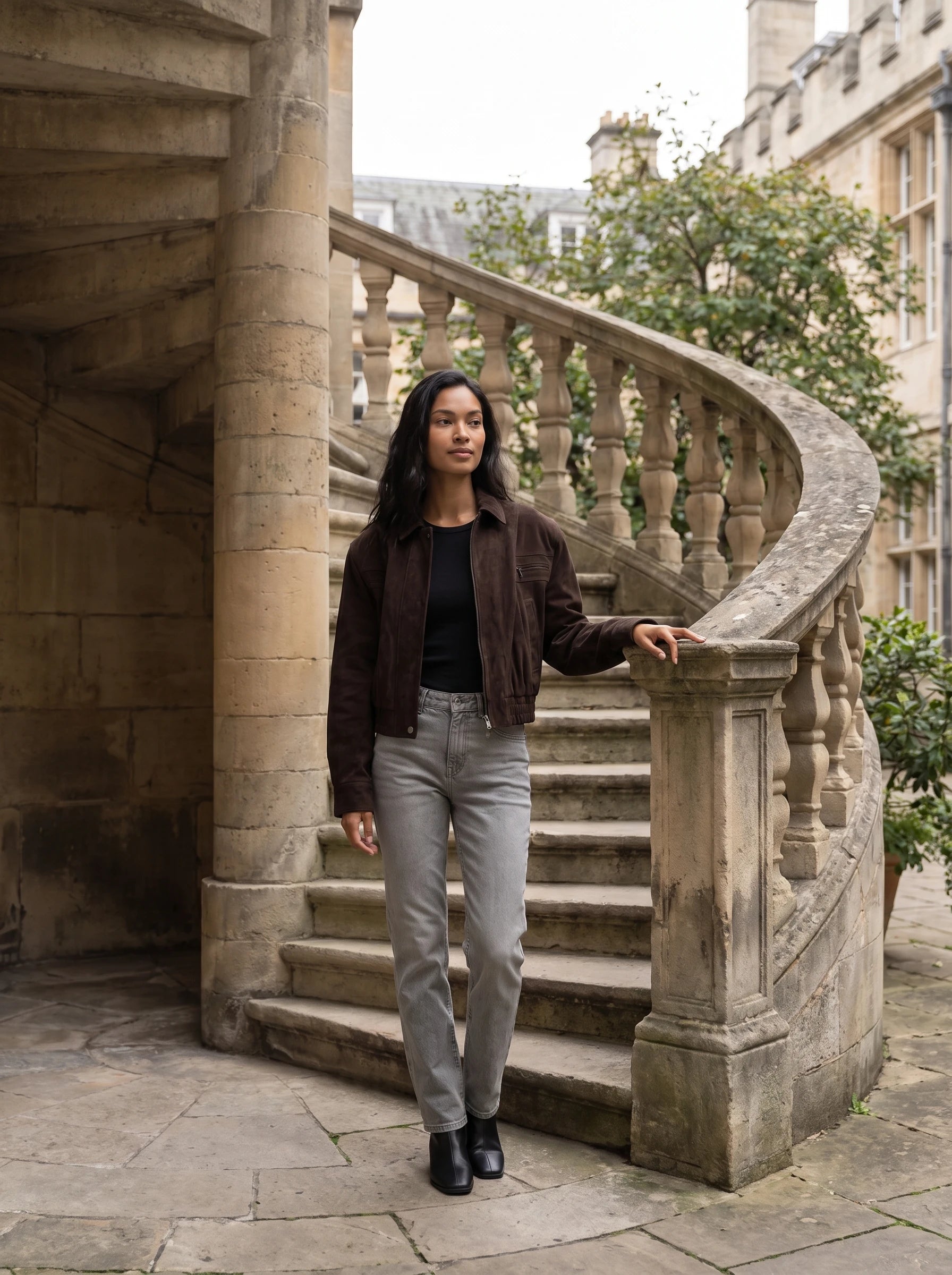 Bomber crop en suédine brun Fabienne, porté près d'un escalier de pierre en colimaçon