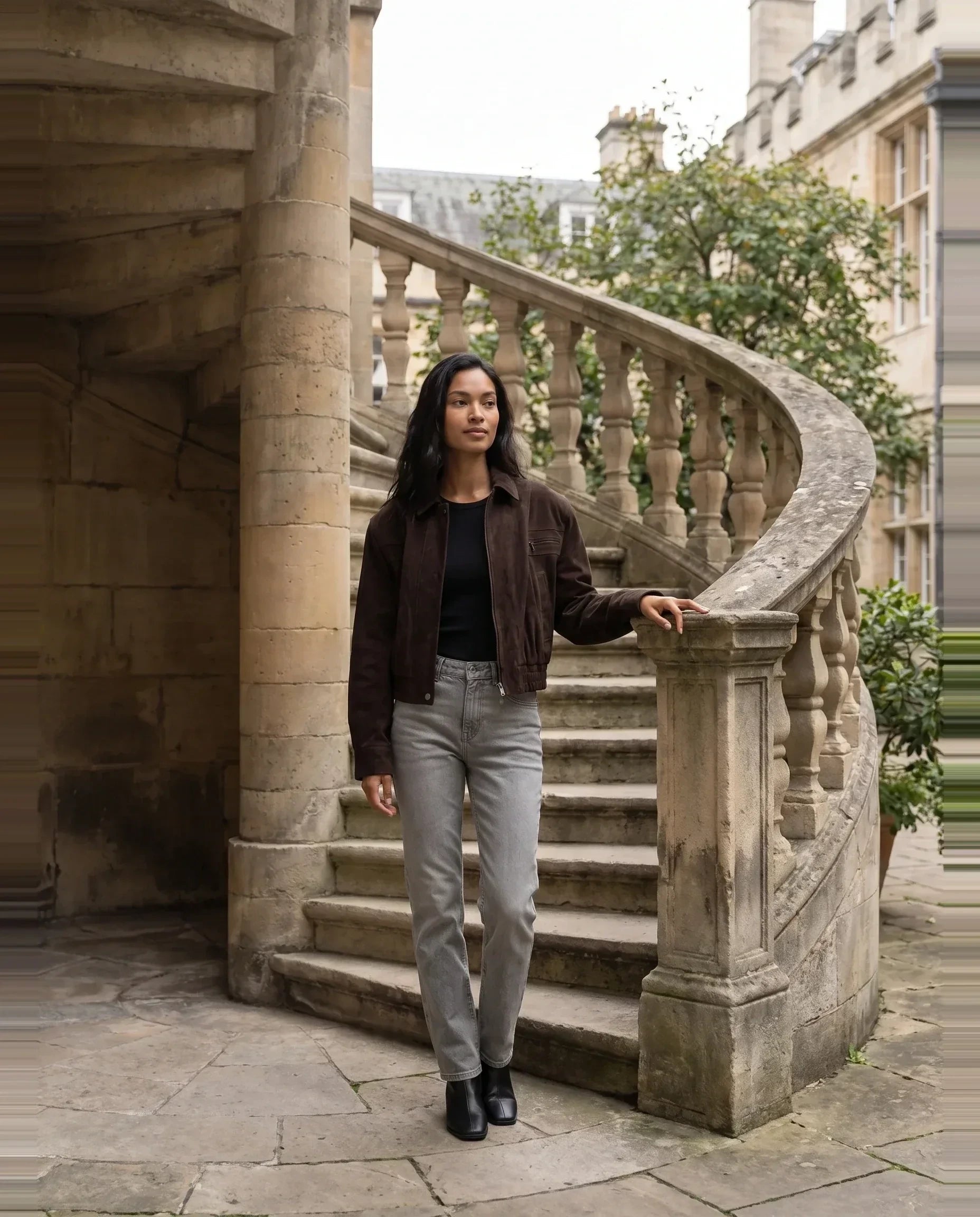 Bomber crop en suédine brun Fabienne, porté près d'un escalier de pierre en colimaçon