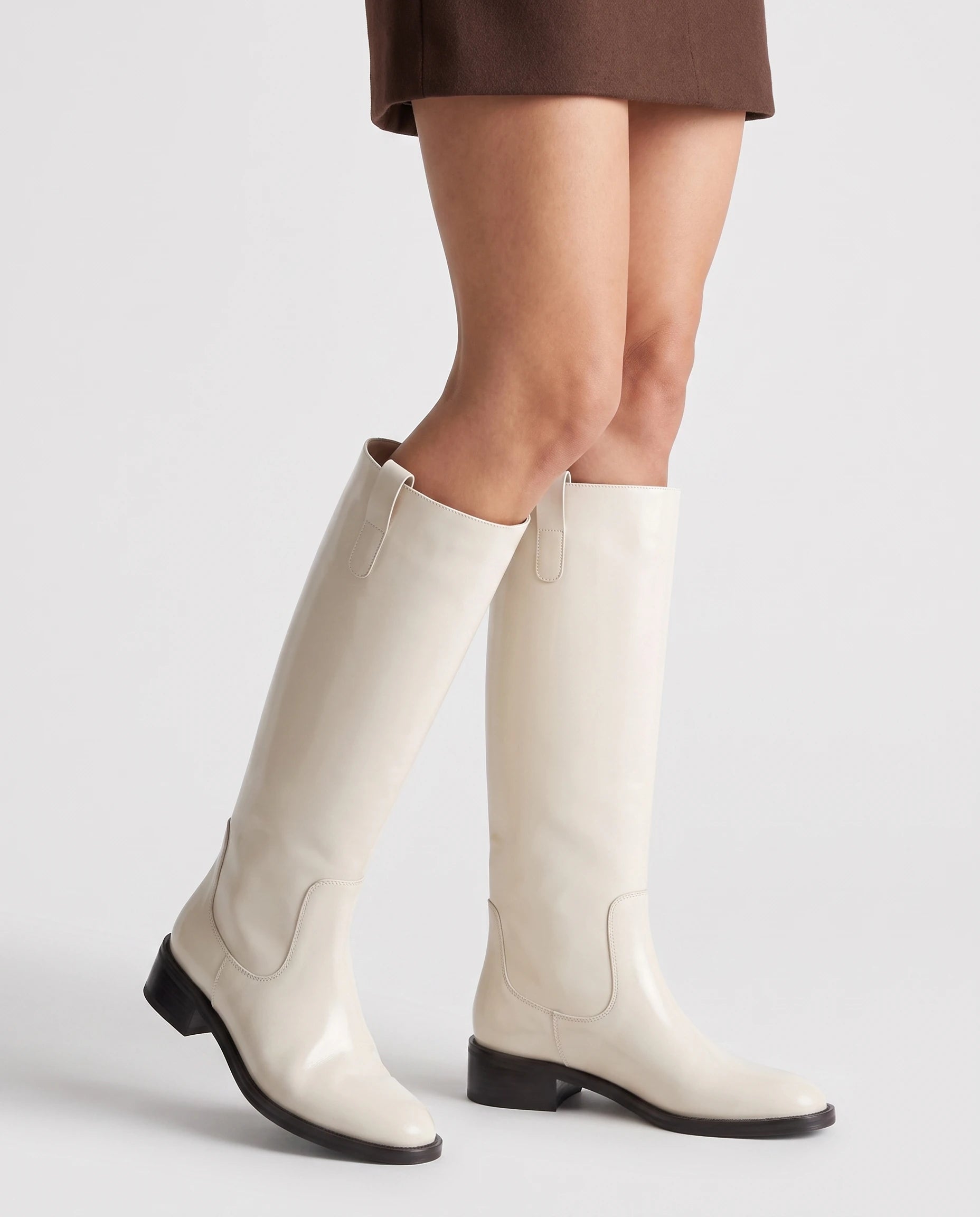 Bottes cavalières hautes effet cuir Bastienne — Blanc Cassé, portées en plan rapproché avec une jupe courte