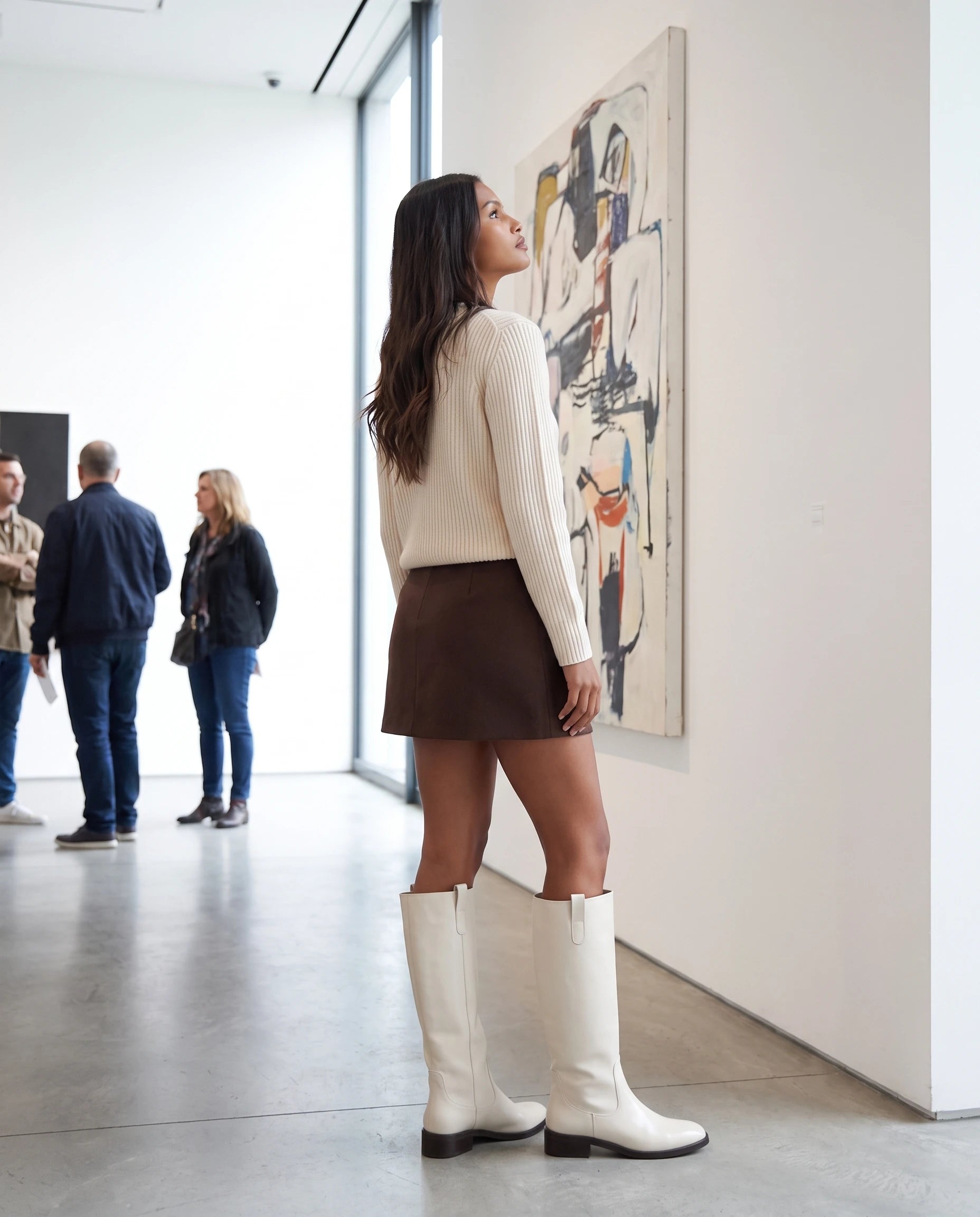 Bottes cavalières hautes effet cuir Bastienne — Blanc Cassé, portées dans une galerie d'art aux murs blancs