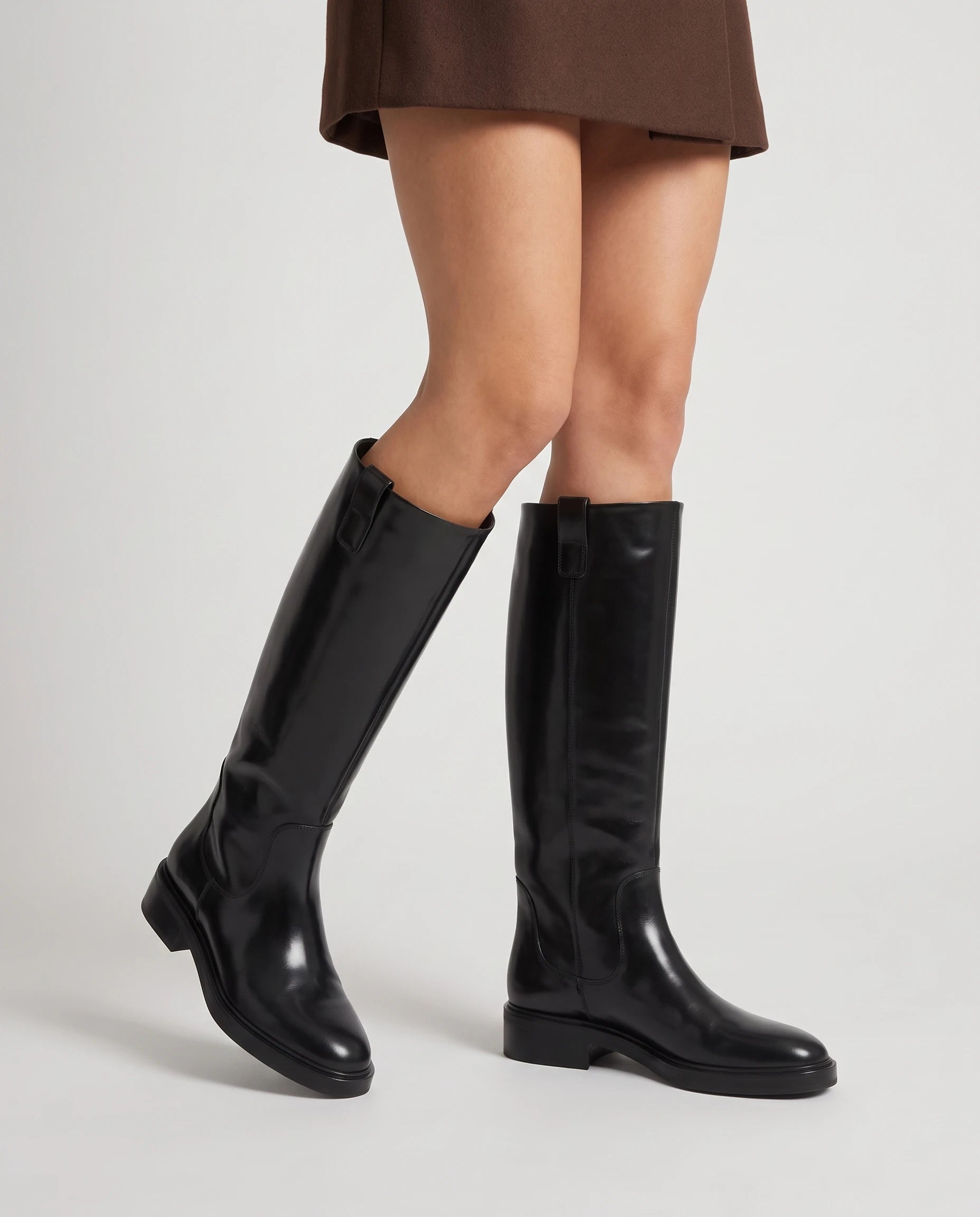 Bottes cavalières hautes effet cuir Bastienne — Noir, portées en plan rapproché avec une jupe courte