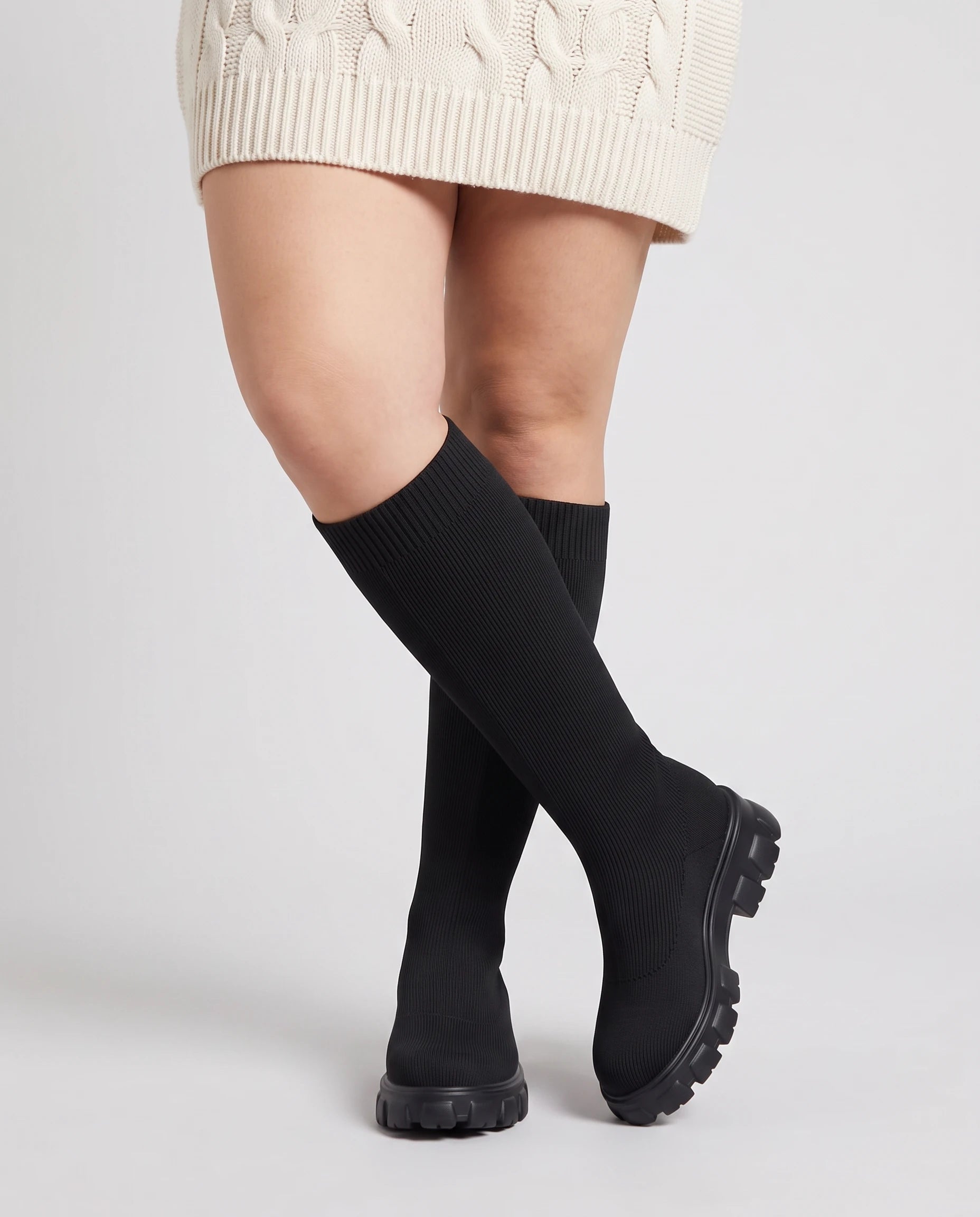 Bottes chaussettes hautes en maille Sylvette — Noir, portées en plan rapproché, chevilles croisées