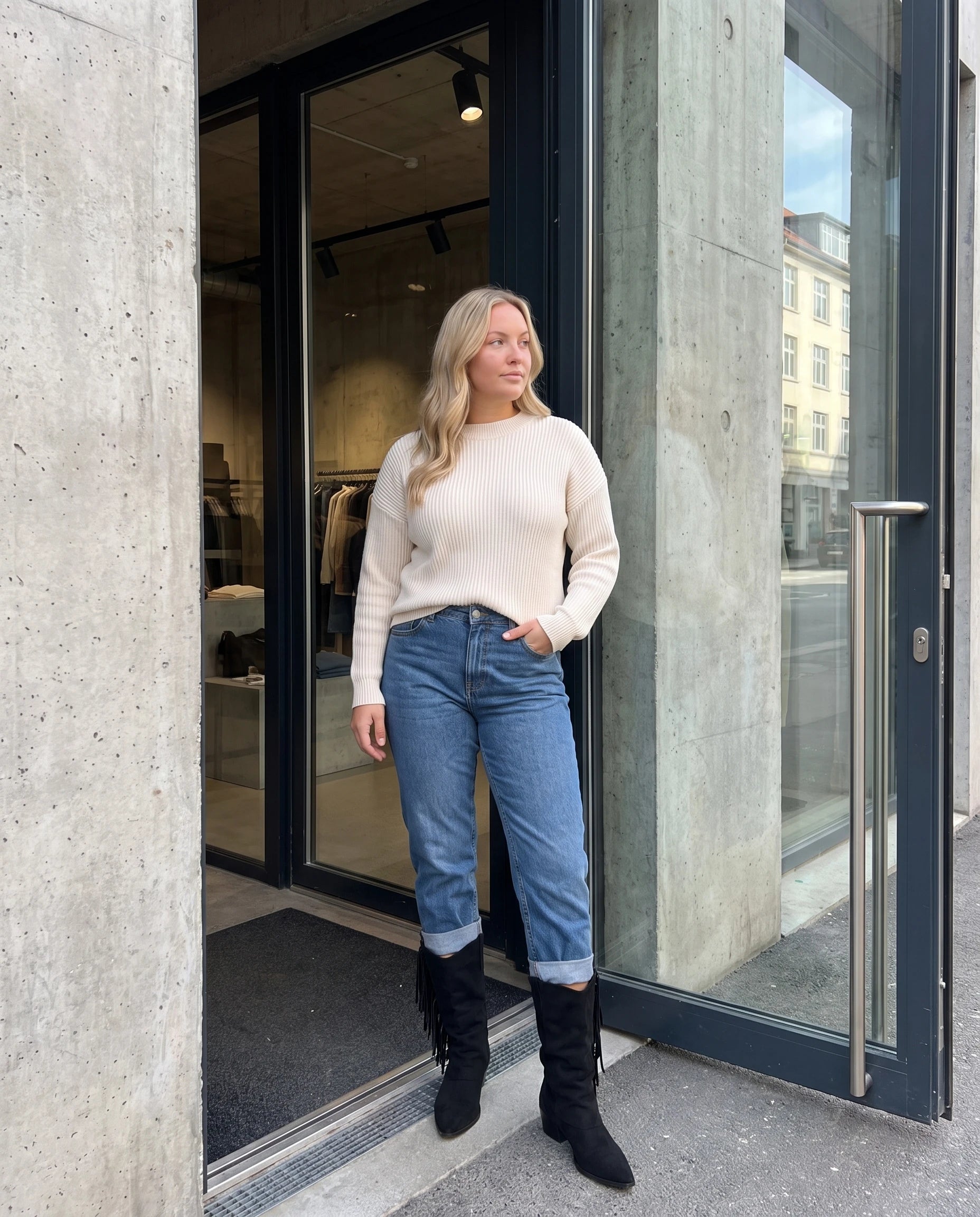 Bottes mi-mollet à franges et bout pointu Pascaline — Noir, portées devant l'entrée d'un concept store