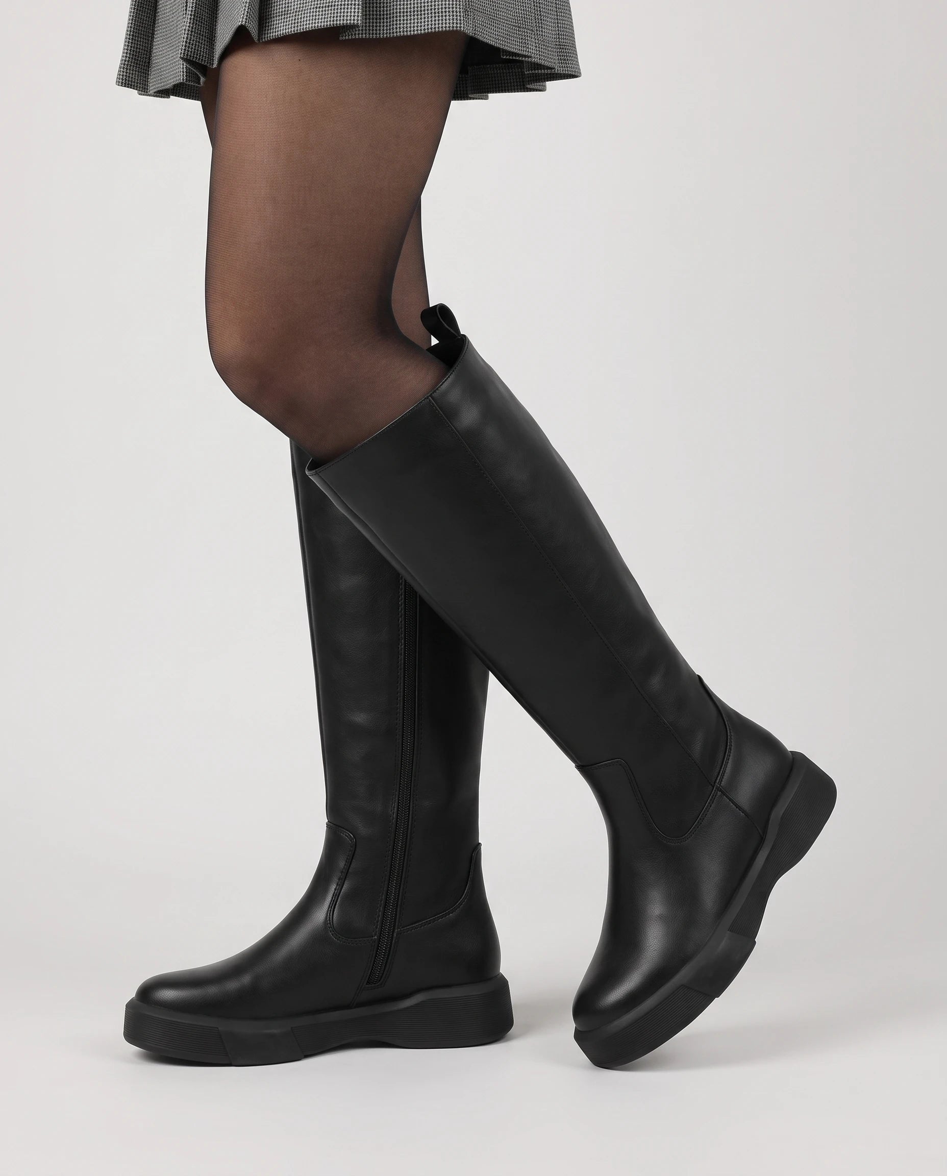 Bottes hautes zippées à semelle épaisse Justine — Noir, portées en plan rapproché avec une jupe plissée