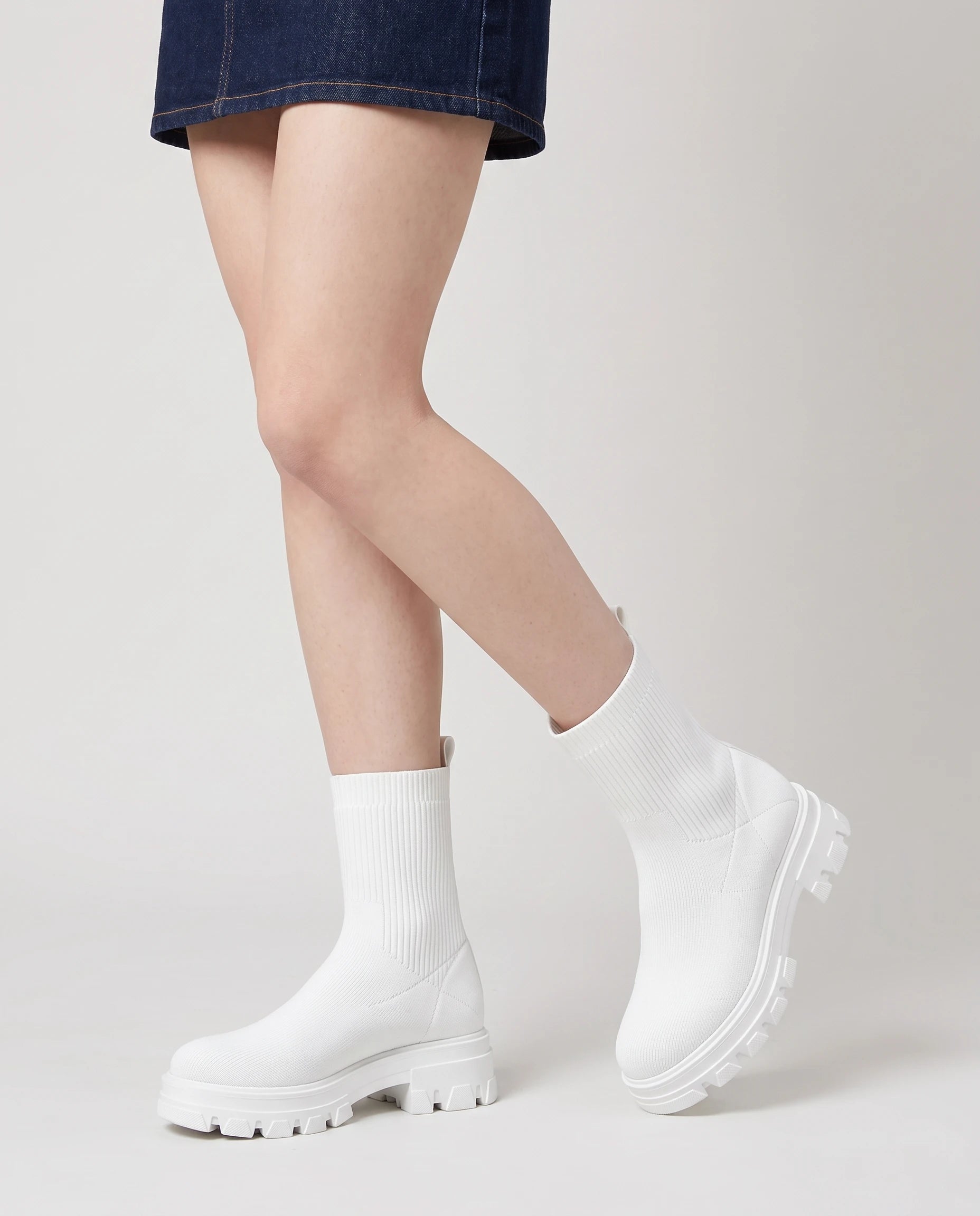 Bottines chaussettes à plateforme Antoinette — Blanc, portées en plan rapproché, un pied sur la pointe