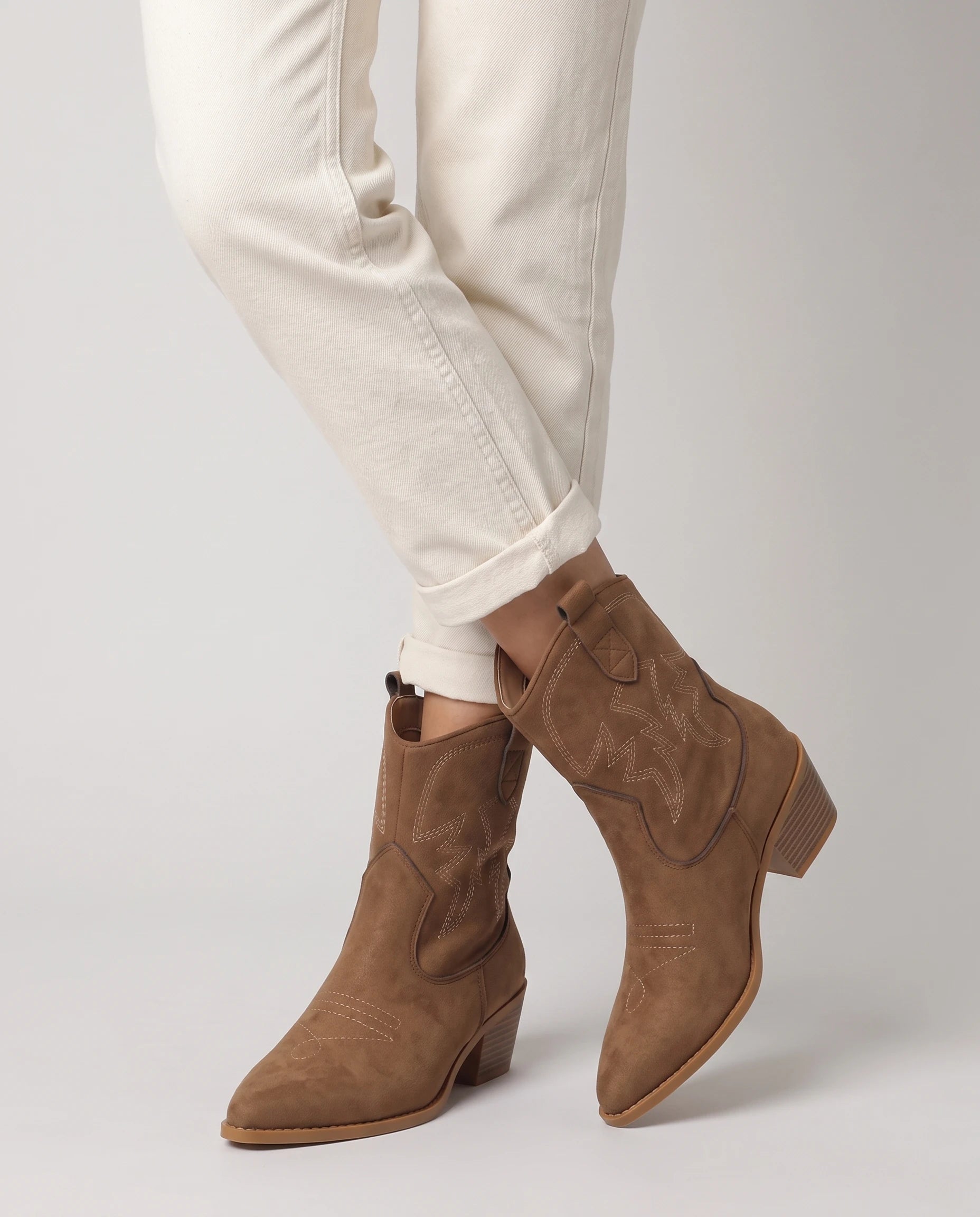 Bottines santiags basses en suédine Yvonne — Chocolat, portées en plan rapproché, chevilles croisées