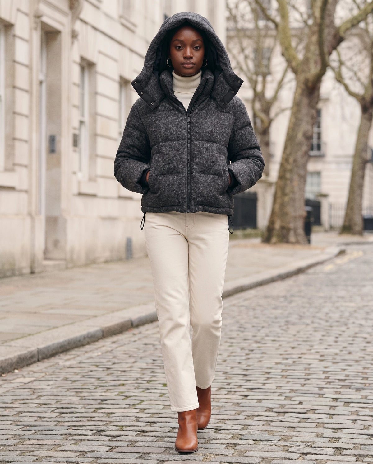 Kurze Steppjacke in Anthrazit Océane mit aufgesetzter Kapuze in einer winterlichen Kopfsteinpflasterstraße