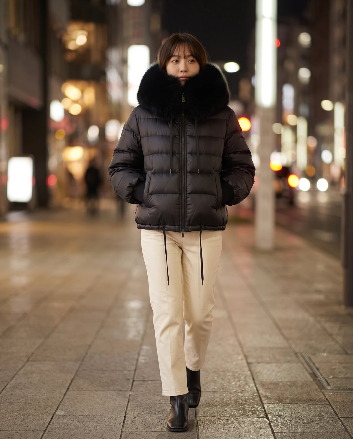 Kurze Steppjacke mit grossem Kunstfellkragen Mila in Schwarz, getragen in einer Stadtstrasse bei Nacht, Kragen hochgestellt