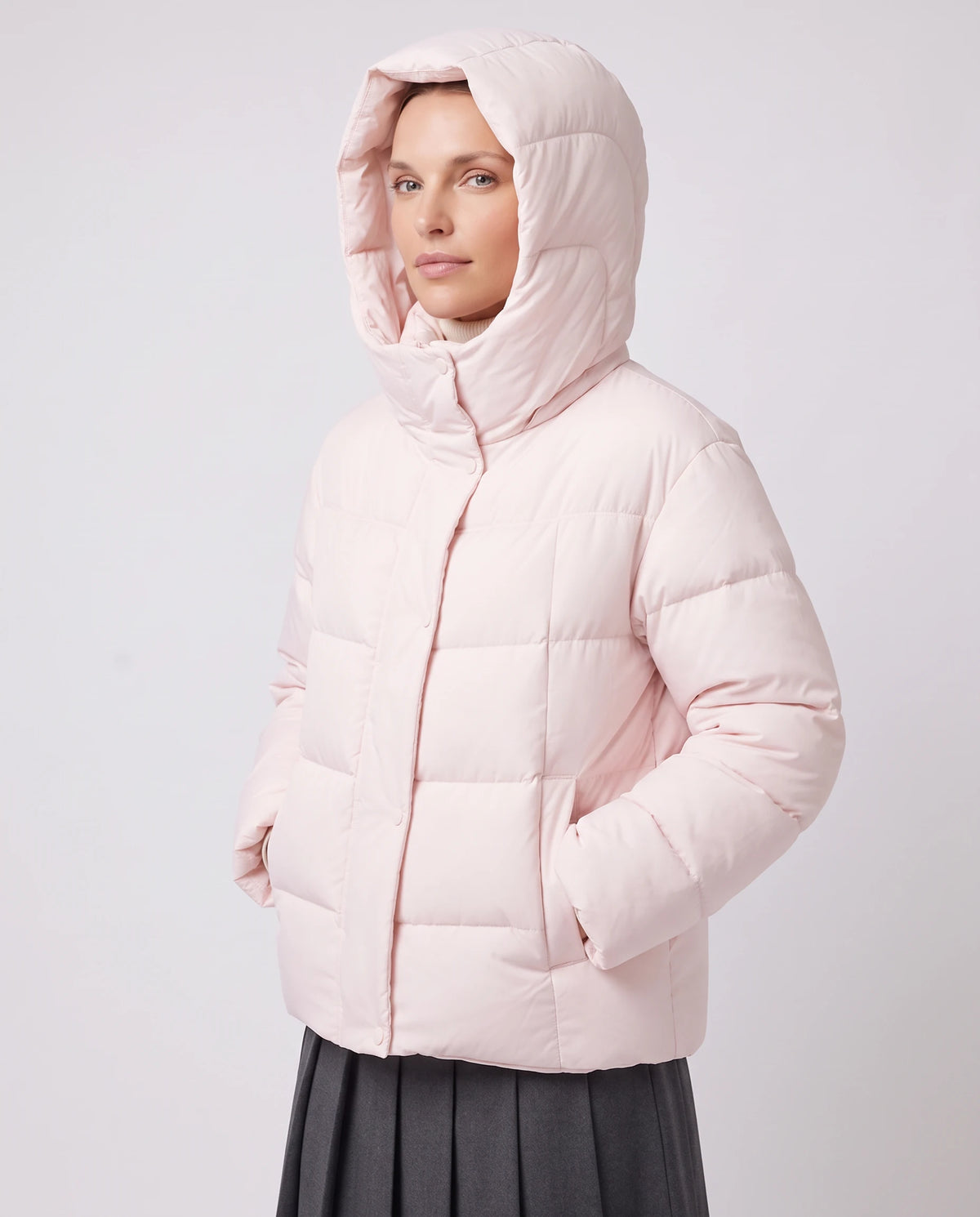 Doudoune courte oversize à grande capuche Maëline rose poudré, capuche relevée, vue de trois quarts en studio