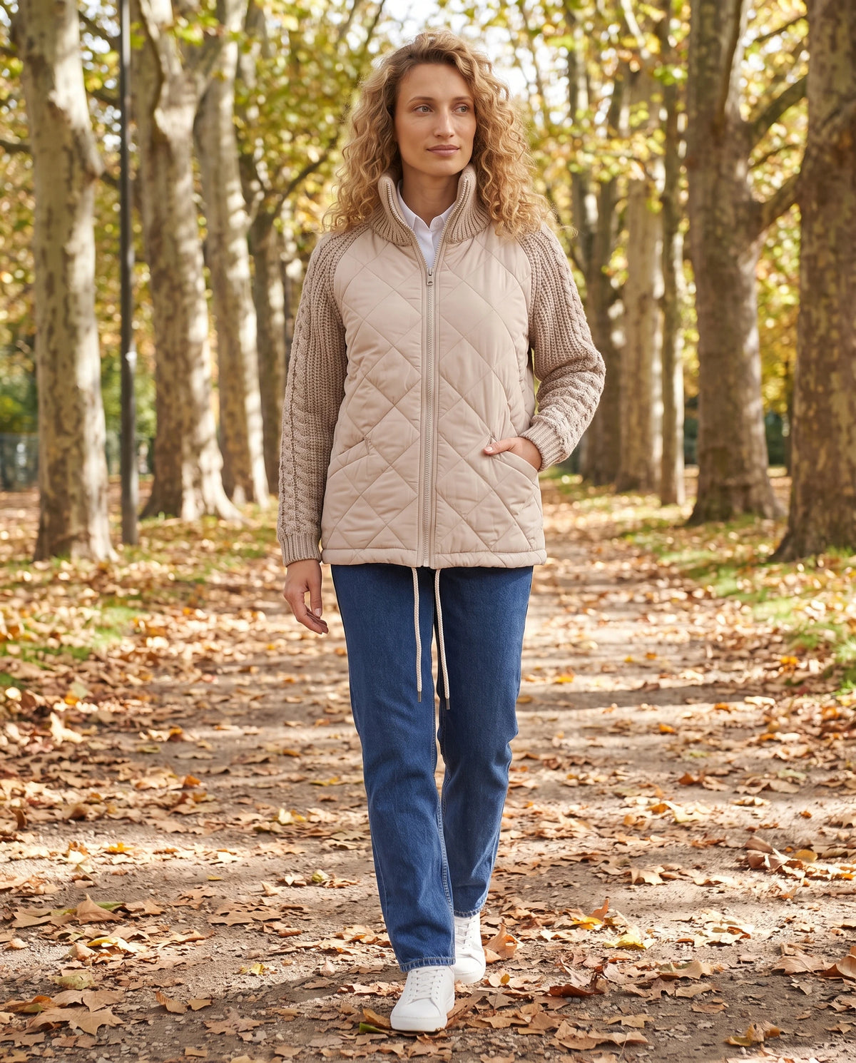 Doudoune courte à manches tricot Emma en Beige, portée dans une allée de platanes en automne