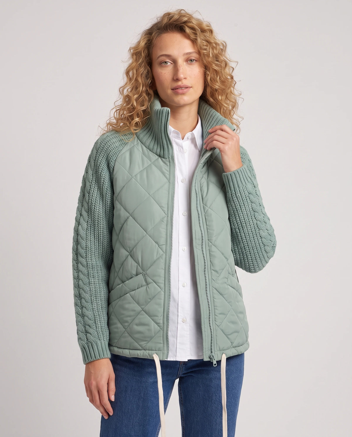 Doudoune courte à manches tricot Emma en Vert Sauge, portée ouverte sur une chemise blanche, plan rapproché