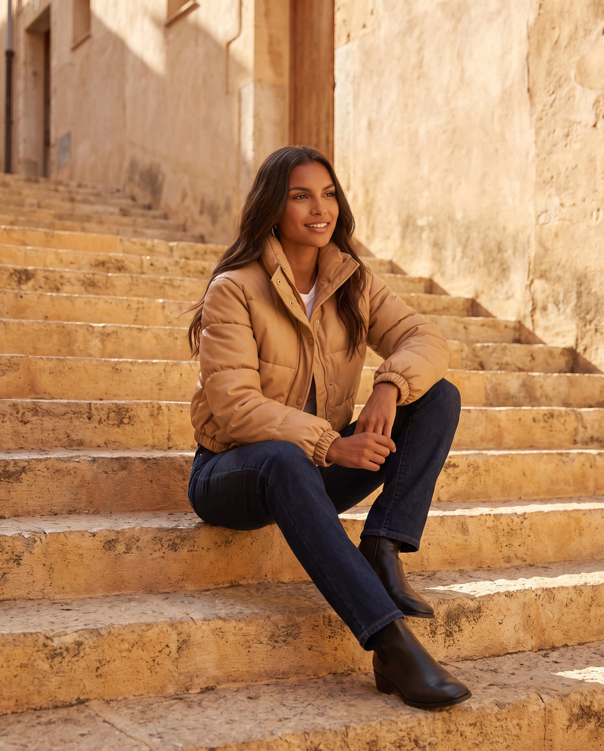 Kurze Steppjacke aus beschichtetem Stoff Alaïs in Camel, getragen auf einer ockerfarbenen Steintreppe