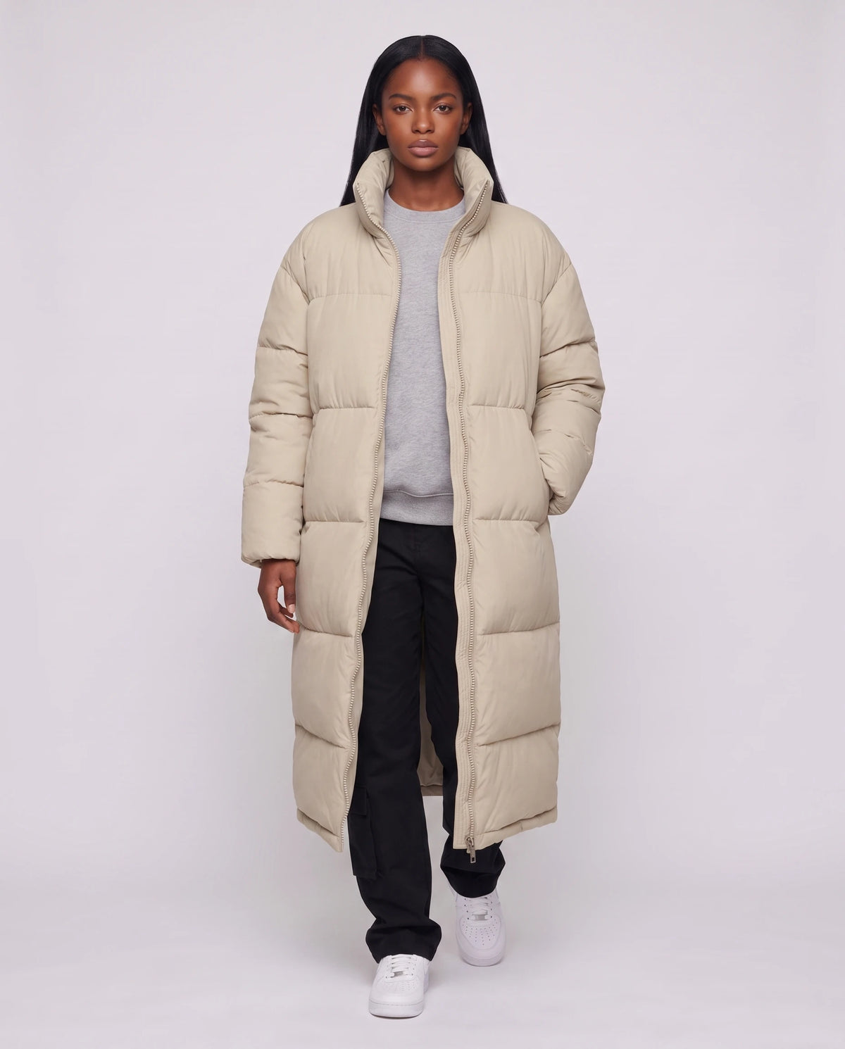 Extralanger Steppmantel mit Stehkragen und Zwei-Wege-Zip Cordélia in Beige, offen getragen über grauem Sweatshirt, Reissverschluss offen