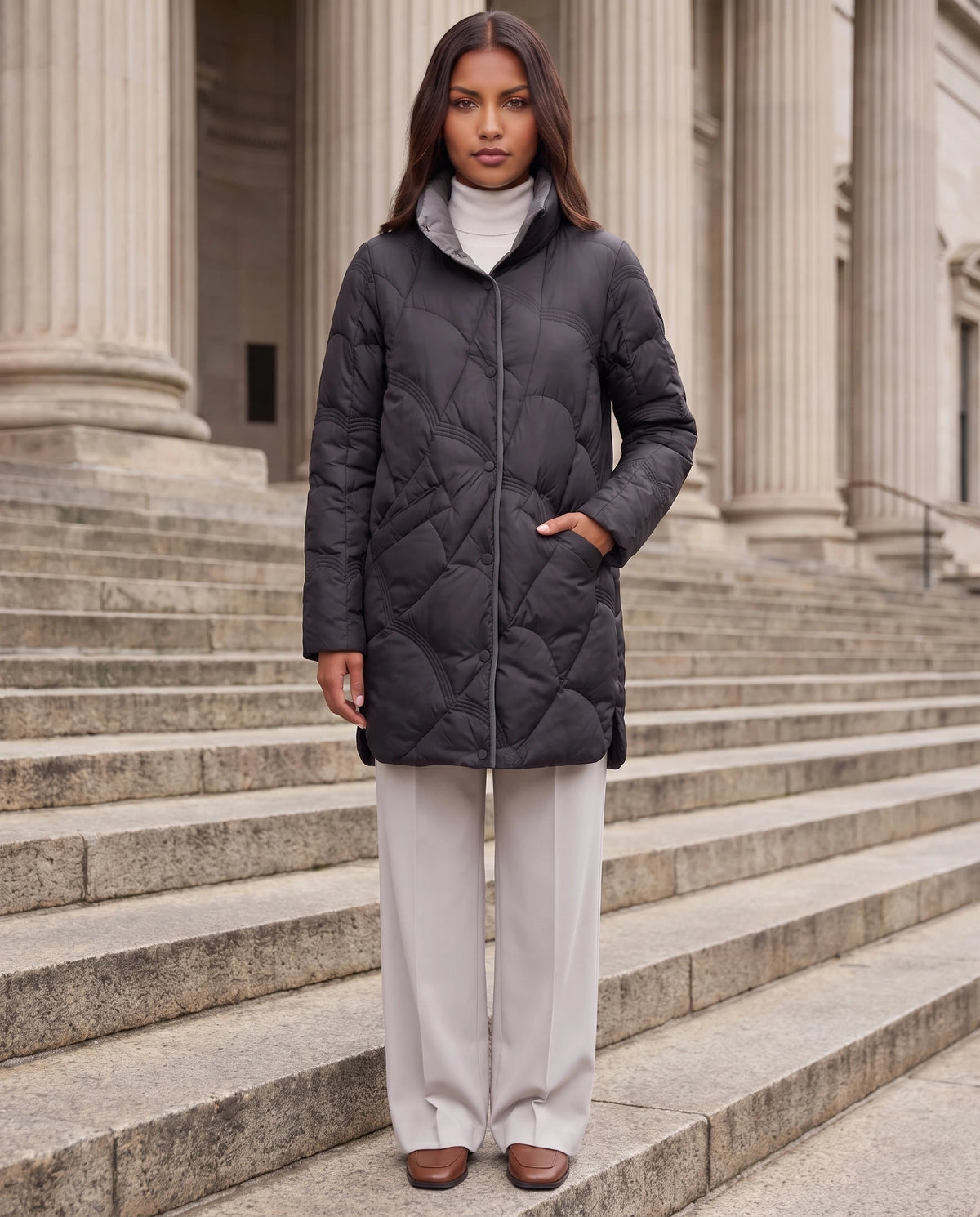 Leichte mittellange Steppjacke mit Wellensteppung Ludmila in Schwarz, getragen auf den Stufen eines Museums mit Säulen