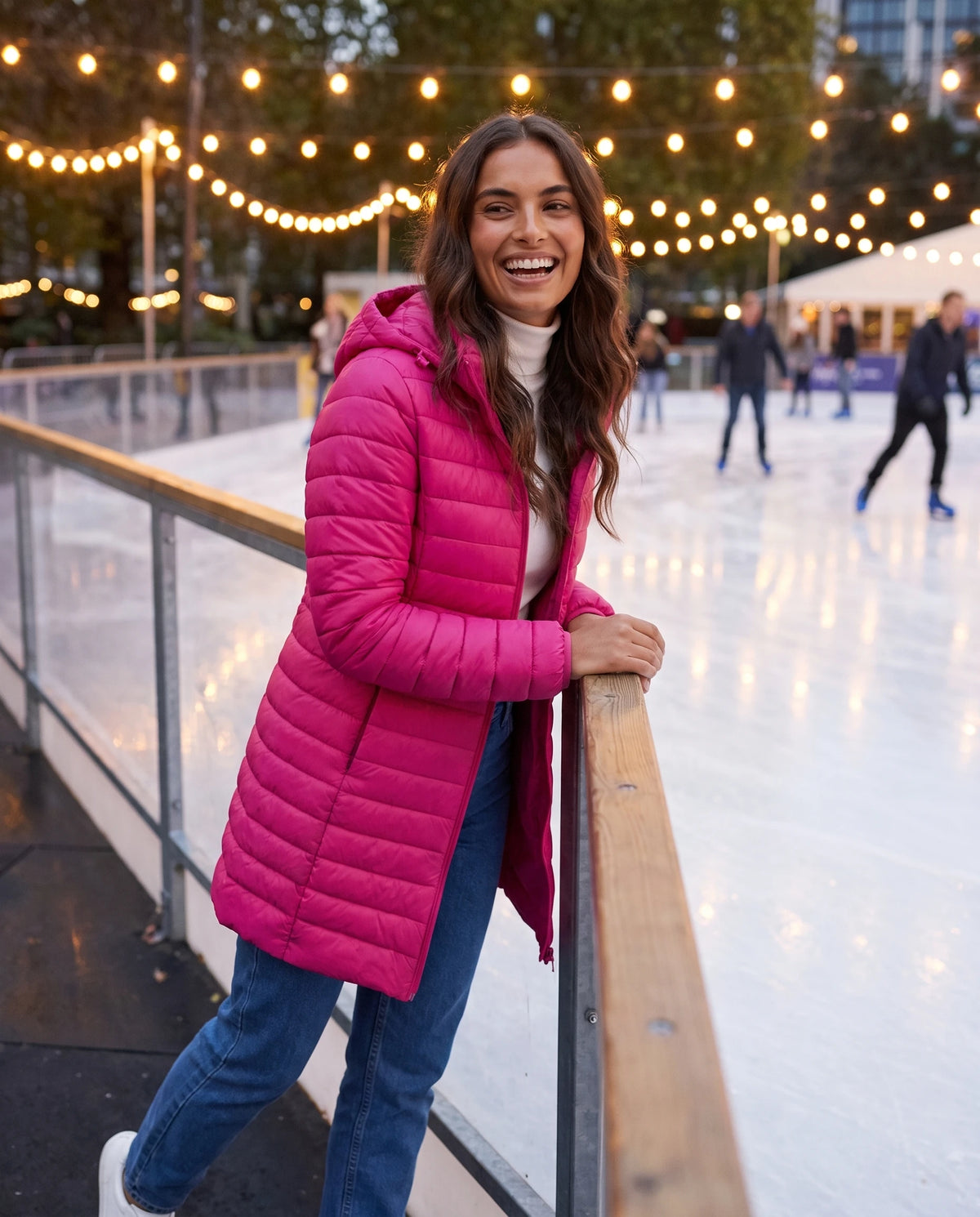 Doudoune légère Nélie en Rose Vif, portée au bord d'une patinoire illuminée