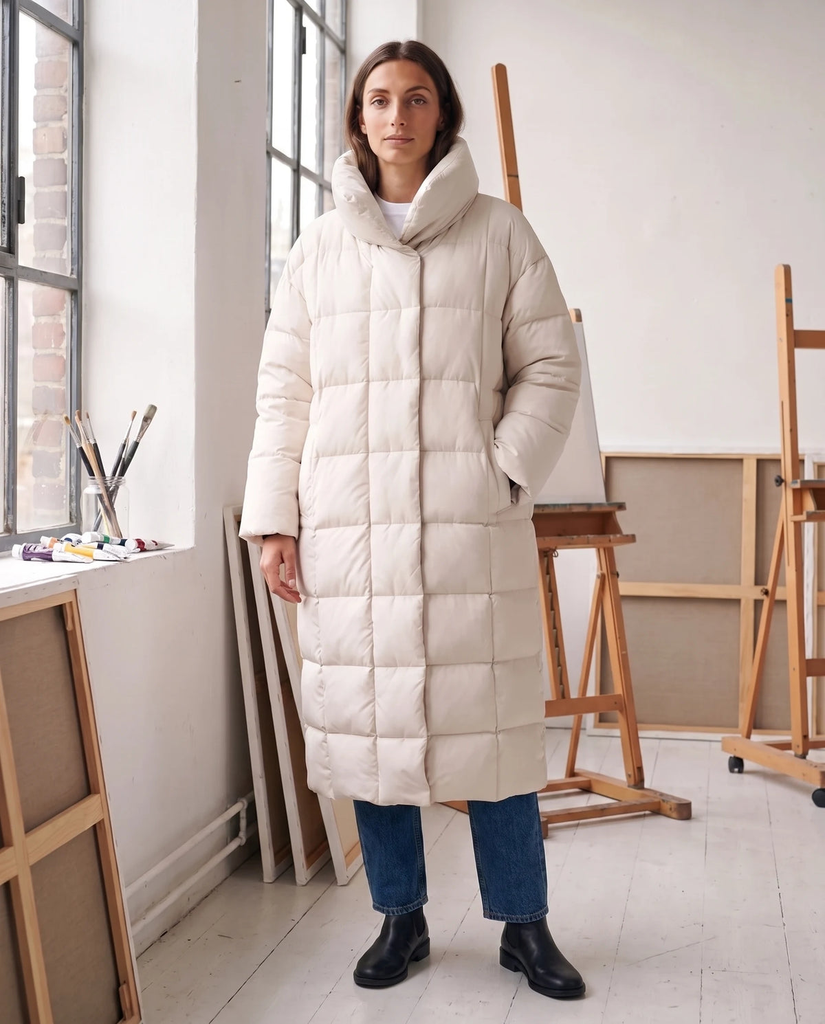 Doudoune longue oversize à col cheminée Laure en Blanc Cassé, portée dans un atelier aux murs blancs