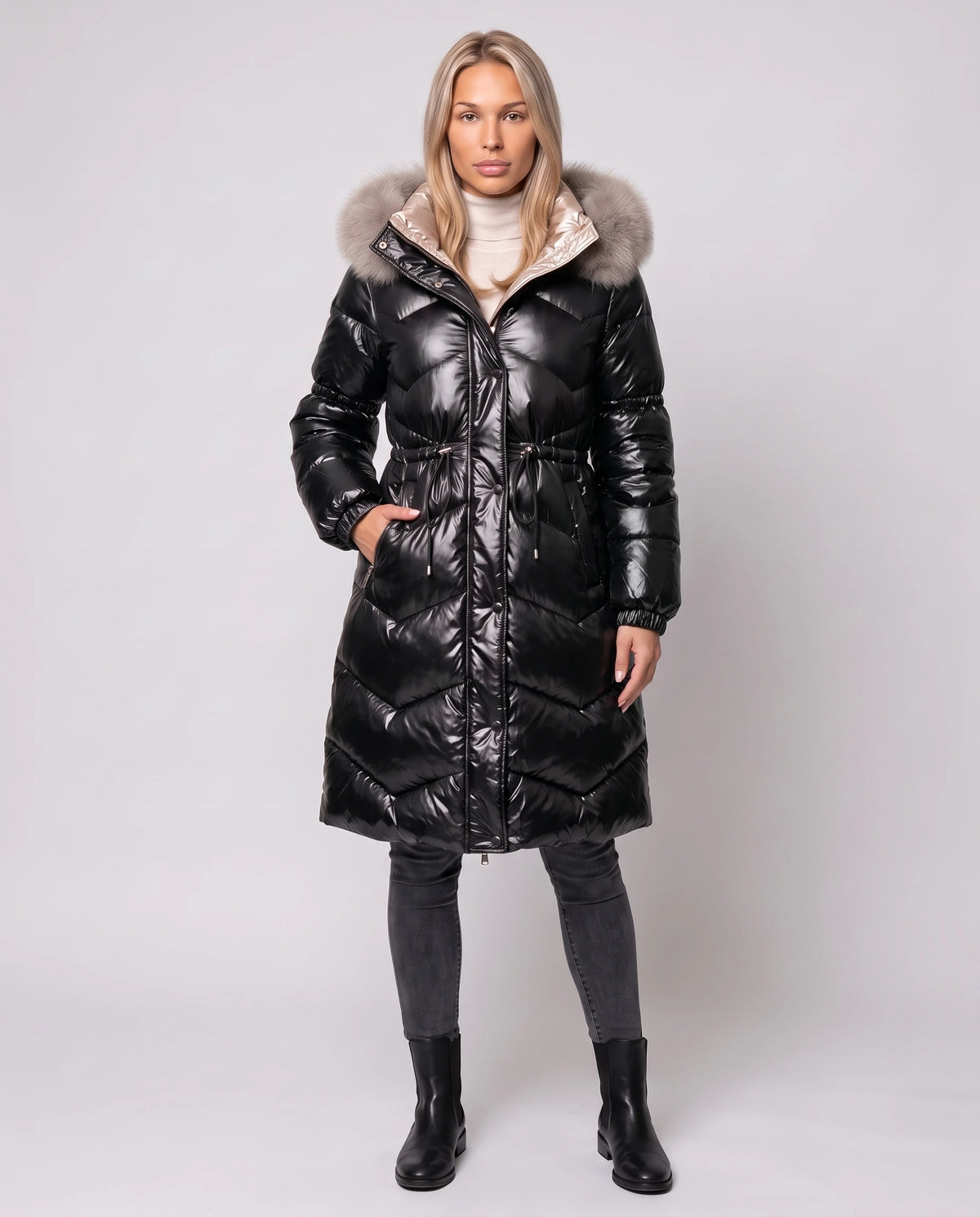 Glänzende mittellange Steppjacke mit Kunstfellkapuze Karine in Schwarz, Vorderansicht in ganzer Länge, geschlossen, Taille gerafft, Kapuze unten