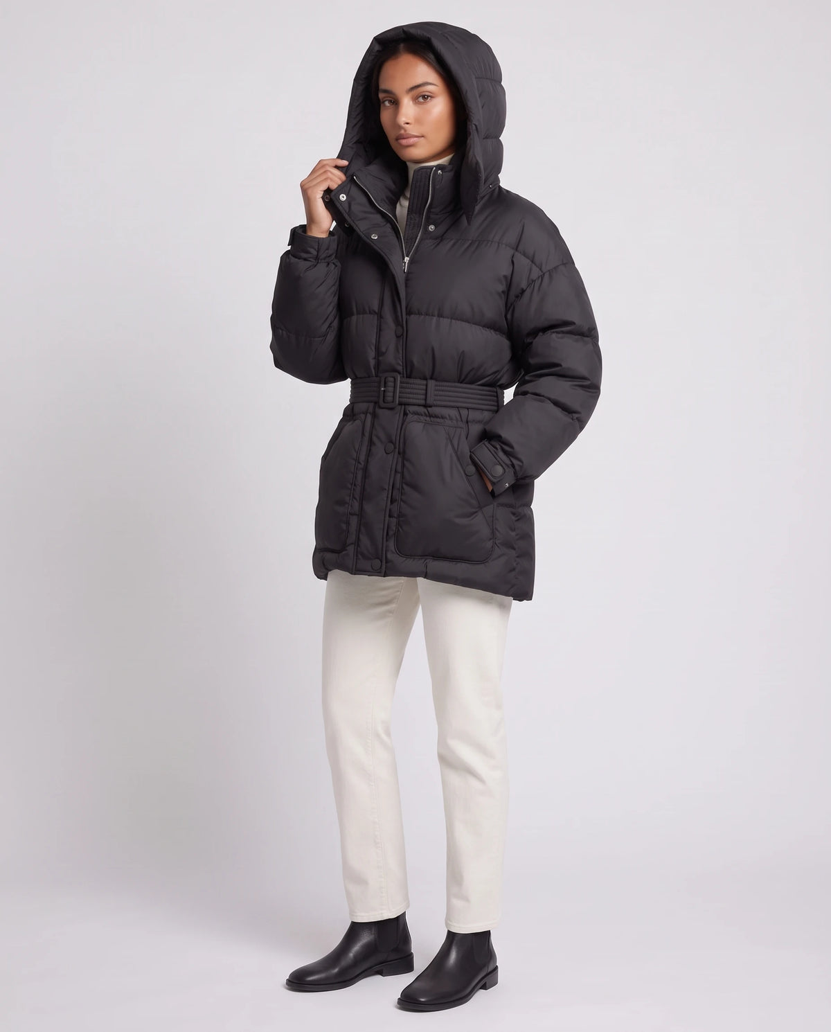 Doudoune oversize mi-cuisse à capuche et ceinture à boucle Sophia en Noir, vue de trois quarts, grande capuche relevée
