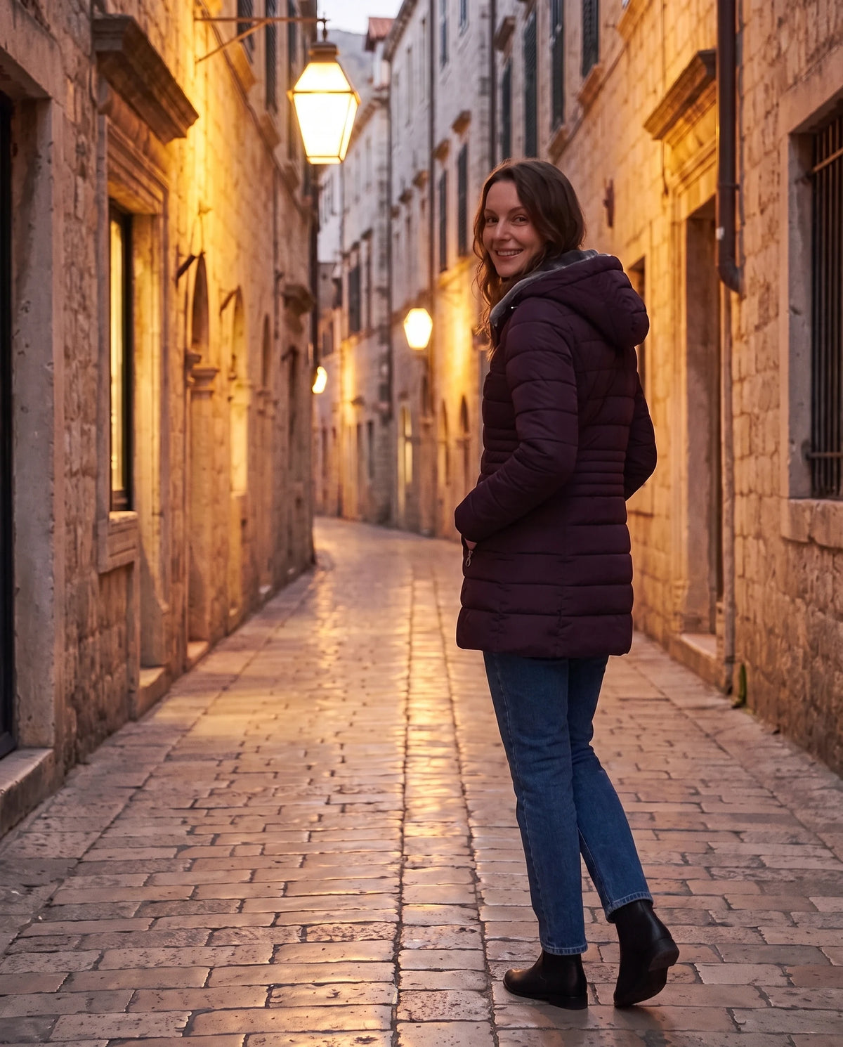 Doudoune doublée polaire Aubine en Prune, portée dans une ruelle ancienne le soir