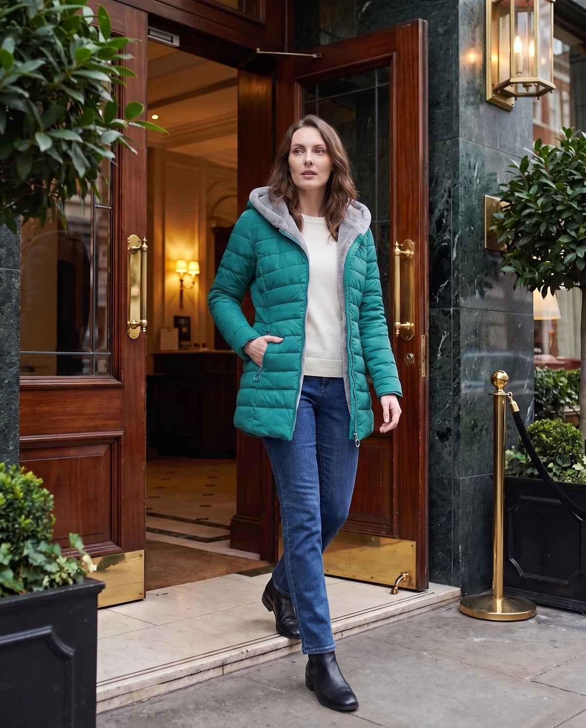 Doudoune doublée polaire Aubine en Vert Émeraude, portée devant une entrée d'hôtel élégante