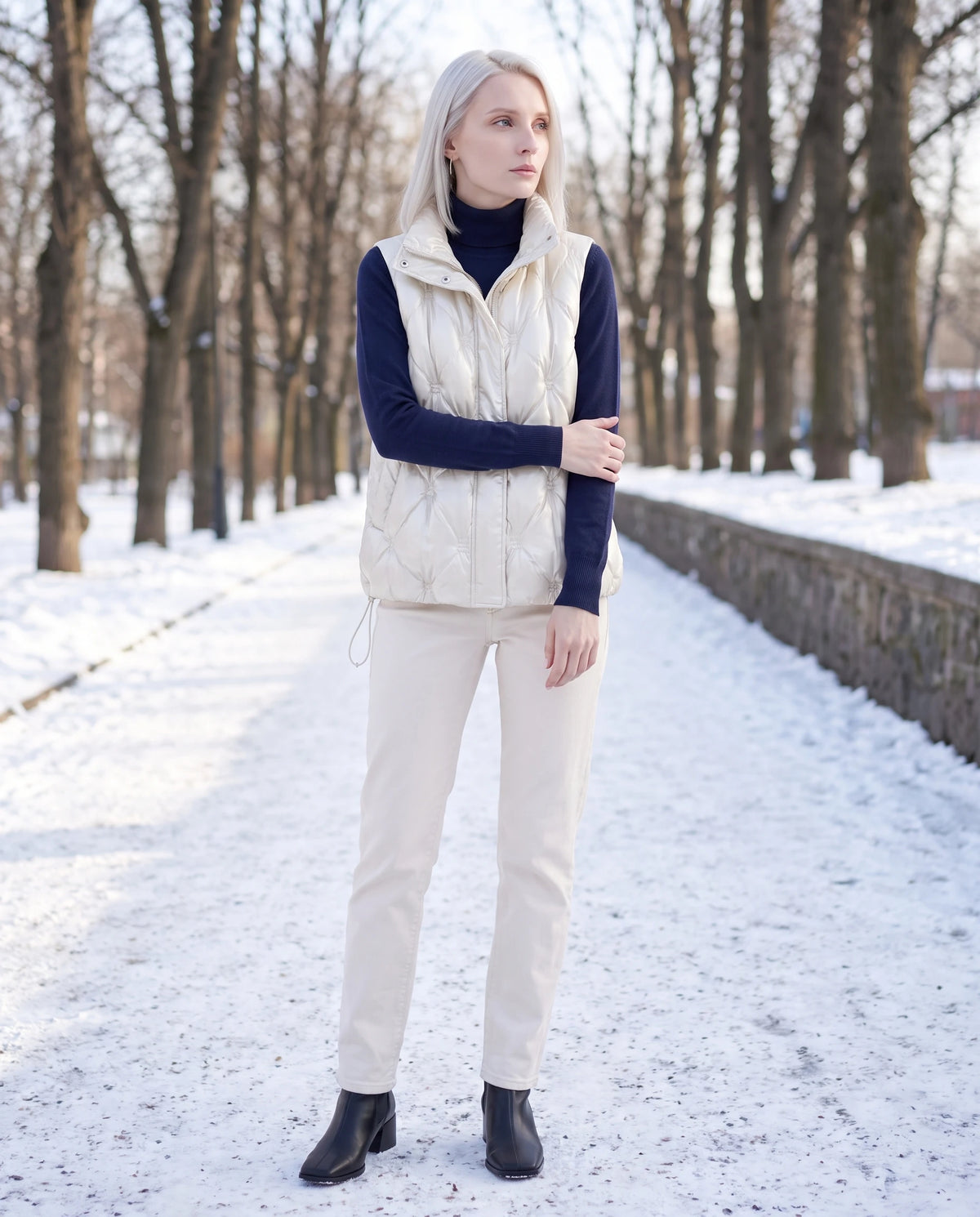 Doudoune sans manches capitonnée en satin Marielle, coloris Blanc Nacré, portée dans une allée de parc enneigée