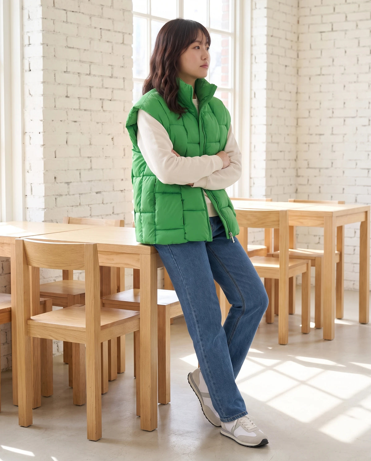 Ärmellose Oversize-Steppweste mit Blockstepp Elvina in Grasgrün, getragen in einem hellen Café mit weiss gestrichenen Ziegelwänden