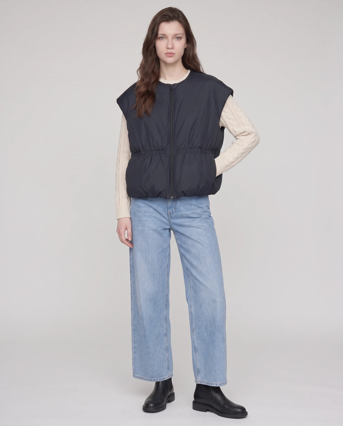 Doudoune sans manches cocon à col rond Béatrix, coloris Noir, plein pied fermée sur pull en maille écru et jean large