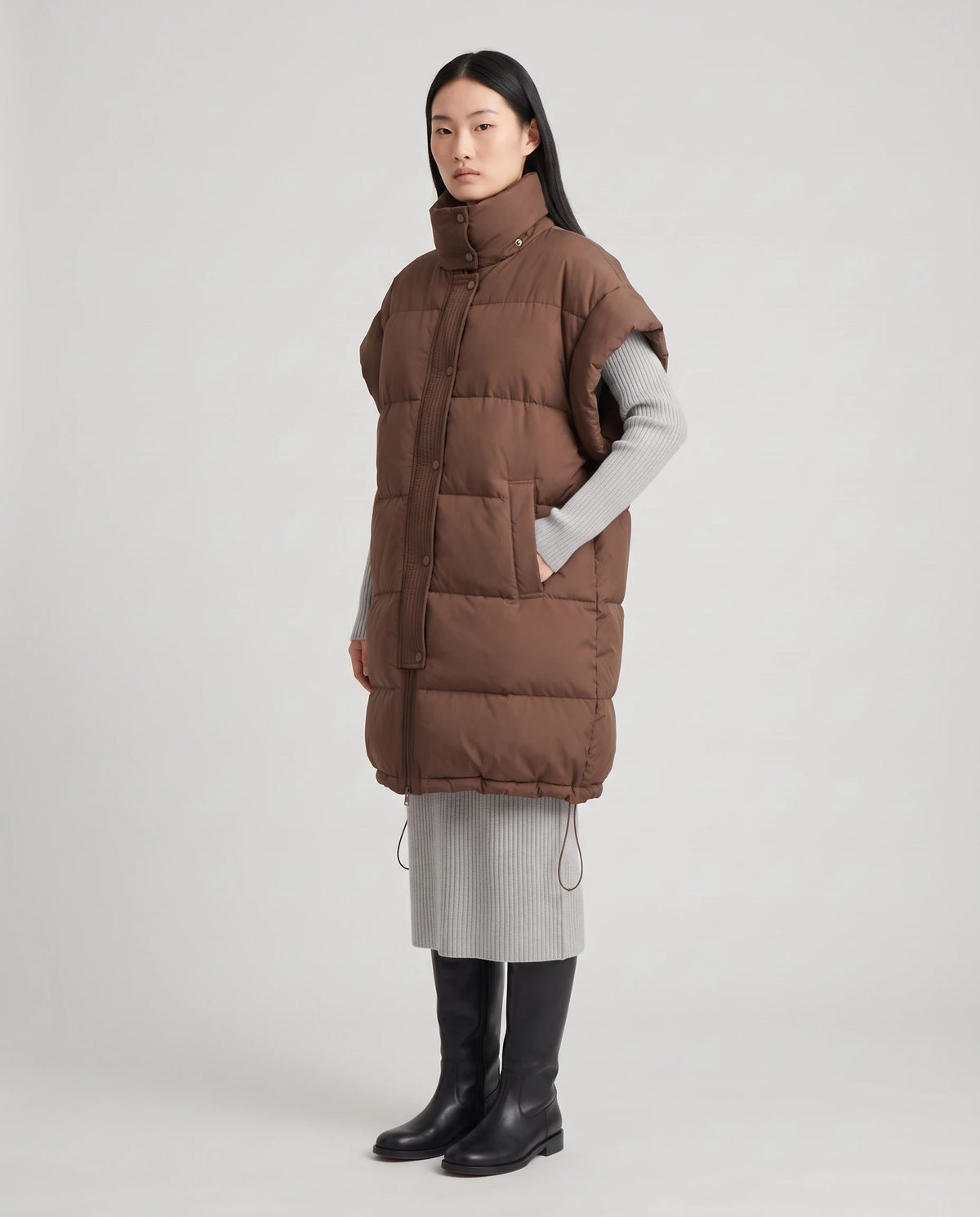 Doudoune sans manches oversize à grand col et patte plissée Perline en Chocolat, vue en pied de trois quarts, main dans une poche passepoilée