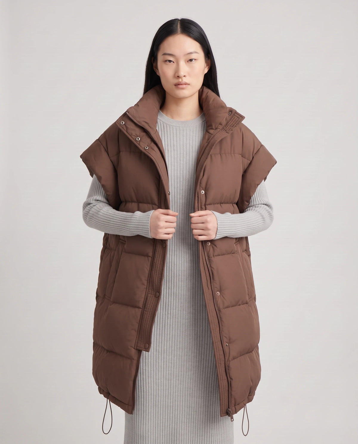 Doudoune sans manches oversize à grand col et patte plissée Perline en Chocolat, portée ouverte sur une robe-pull gris perle, plan rapproché