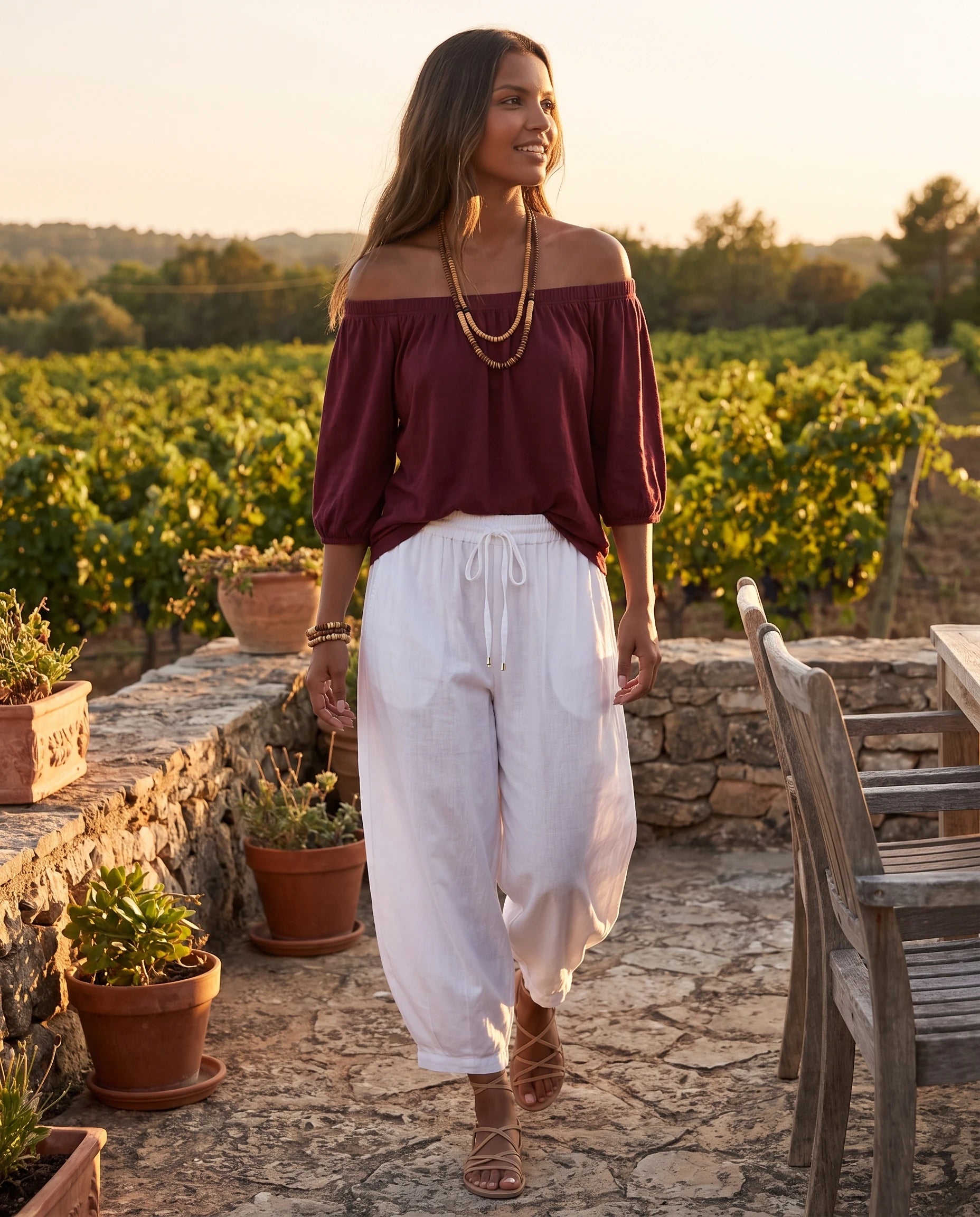Ensemble epaules denudees et pantalon sarouel Bordeaux portee sur une terrasse de vignoble au crepuscule - Lorene | Zolena