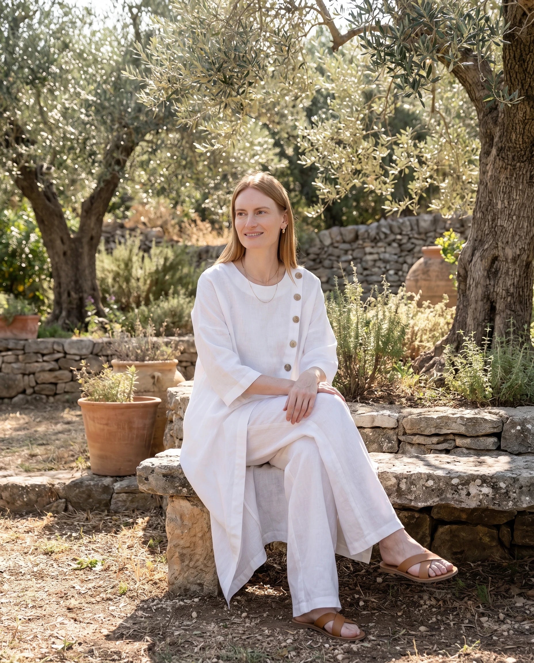 Ensemble tunique longue en lin et pantalon large Blanc assise dans un jardin d oliviers - Ombeline | Zolena