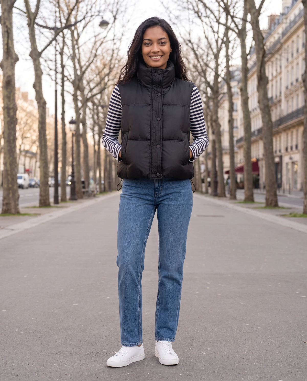 Gilet matelassé cropped à col montant et patte à pressions Soline en Noir, portée sur un boulevard bordé de platanes en hiver