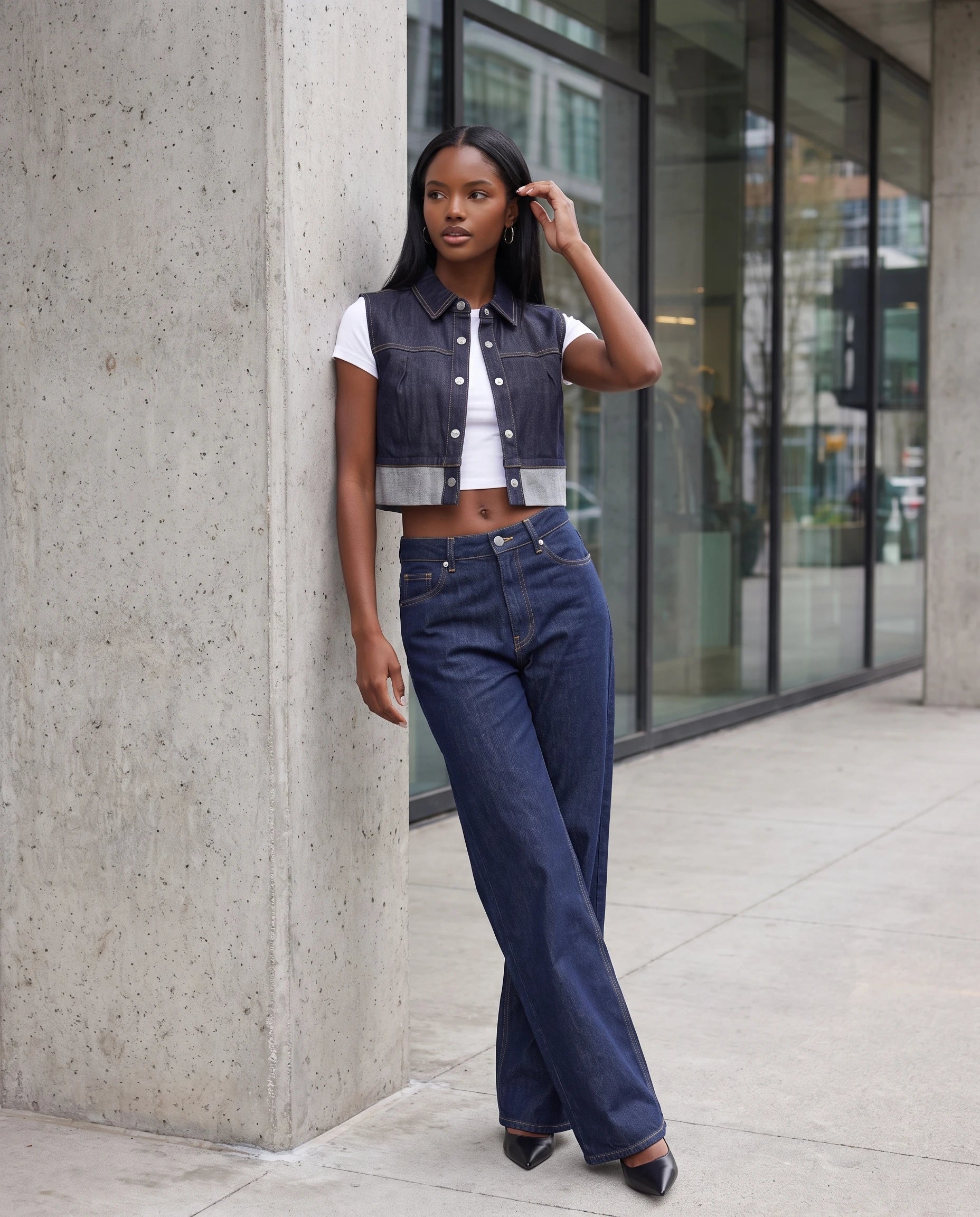 Gilet en jean indigo brut Perle, porté sur une place moderne en béton