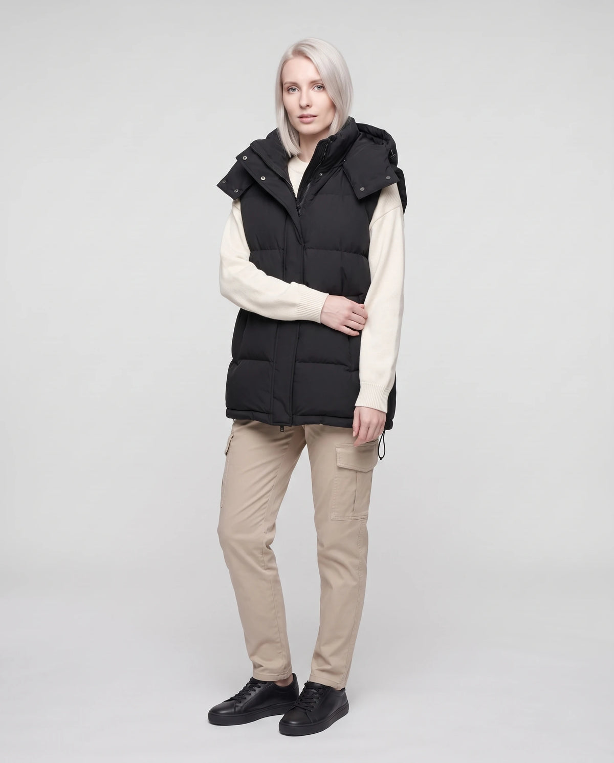 Gilet matelassé oversize à capuche amovible Patricia en Noir, vue de face en pied, larges canaux horizontaux et cordon d’ourlet