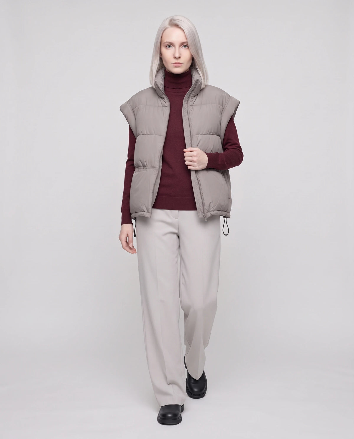 Gilet matelassé sans manches à poches plaquées Anceline en Gris Taupe, porté ouvert sur un col roulé bordeaux, doublure unie visible