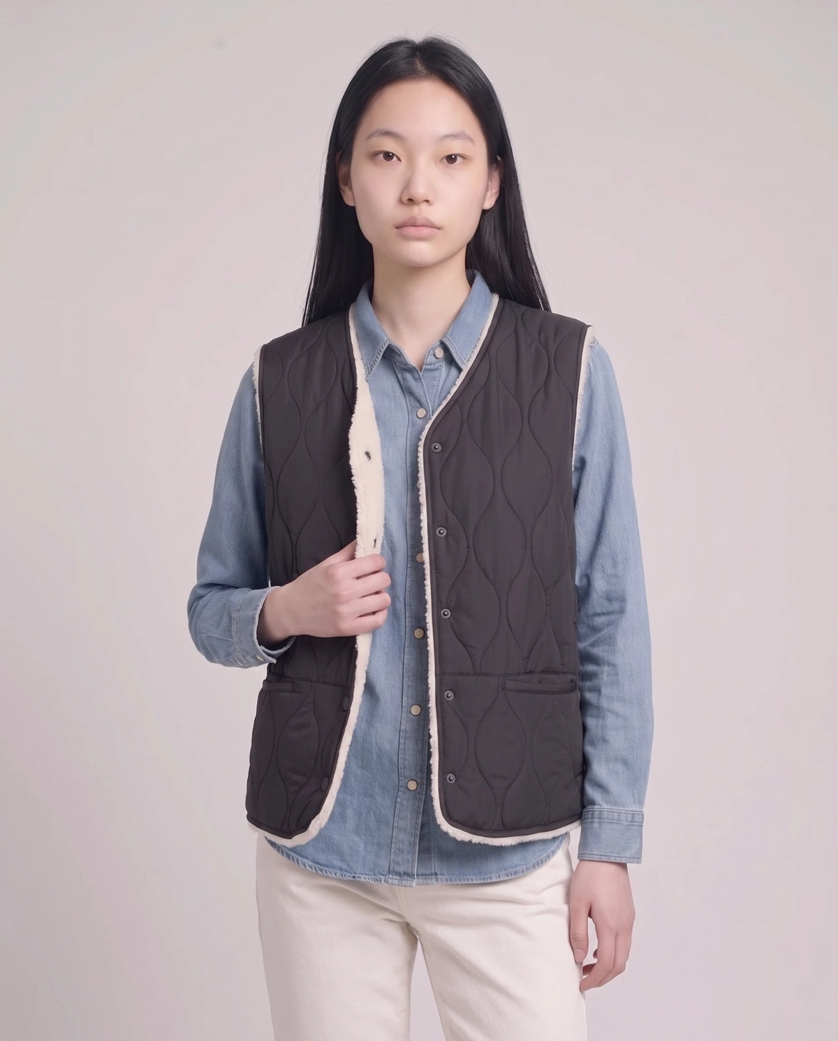 Gilet matelassé doublé sherpa à col V Amaline — Noir, porté ouvert sur une chemise en jean, doublure sherpa visible