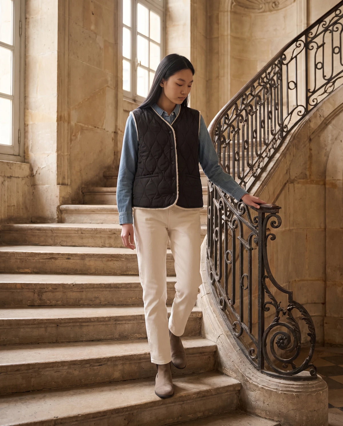 Gilet matelassé doublé sherpa à col V Amaline — Noir, porté dans un escalier en pierre