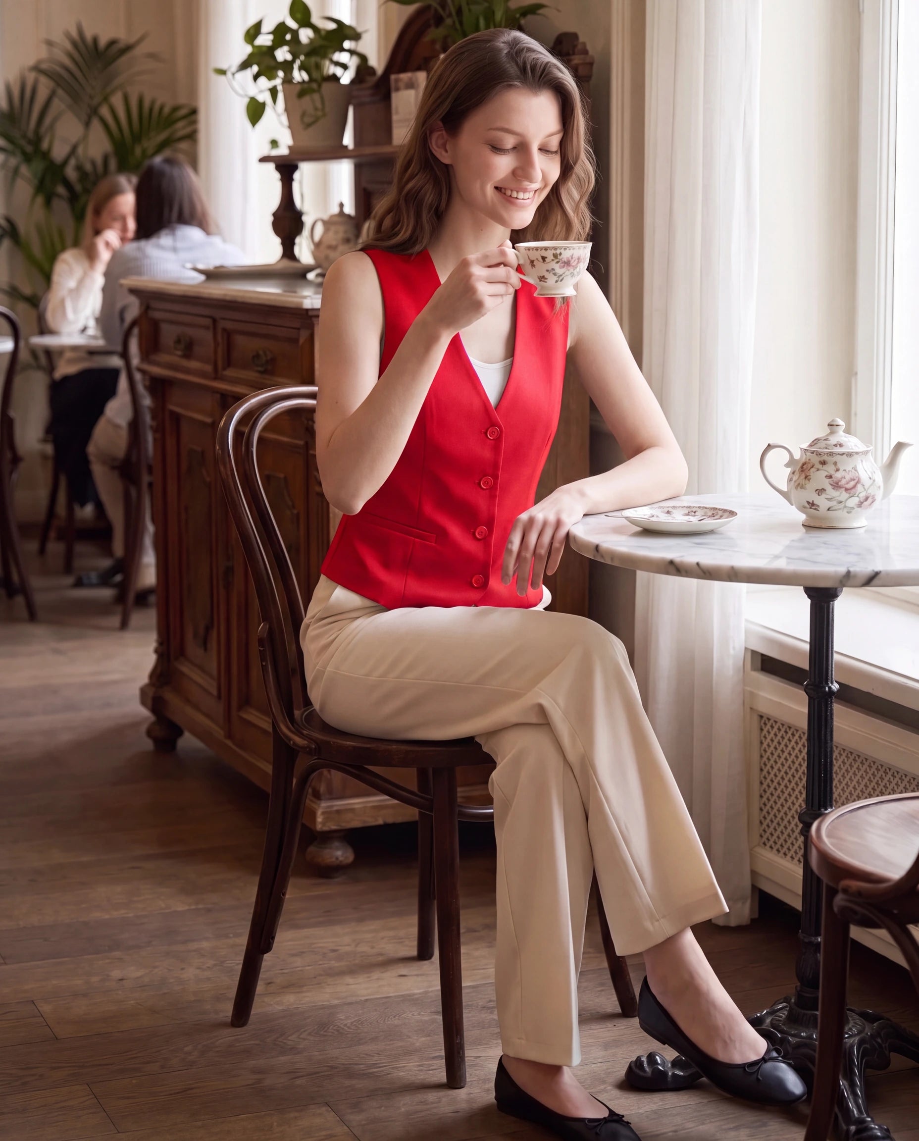 Gilet de tailleur rouge profond Marthe, porté dans un salon de thé élégant
