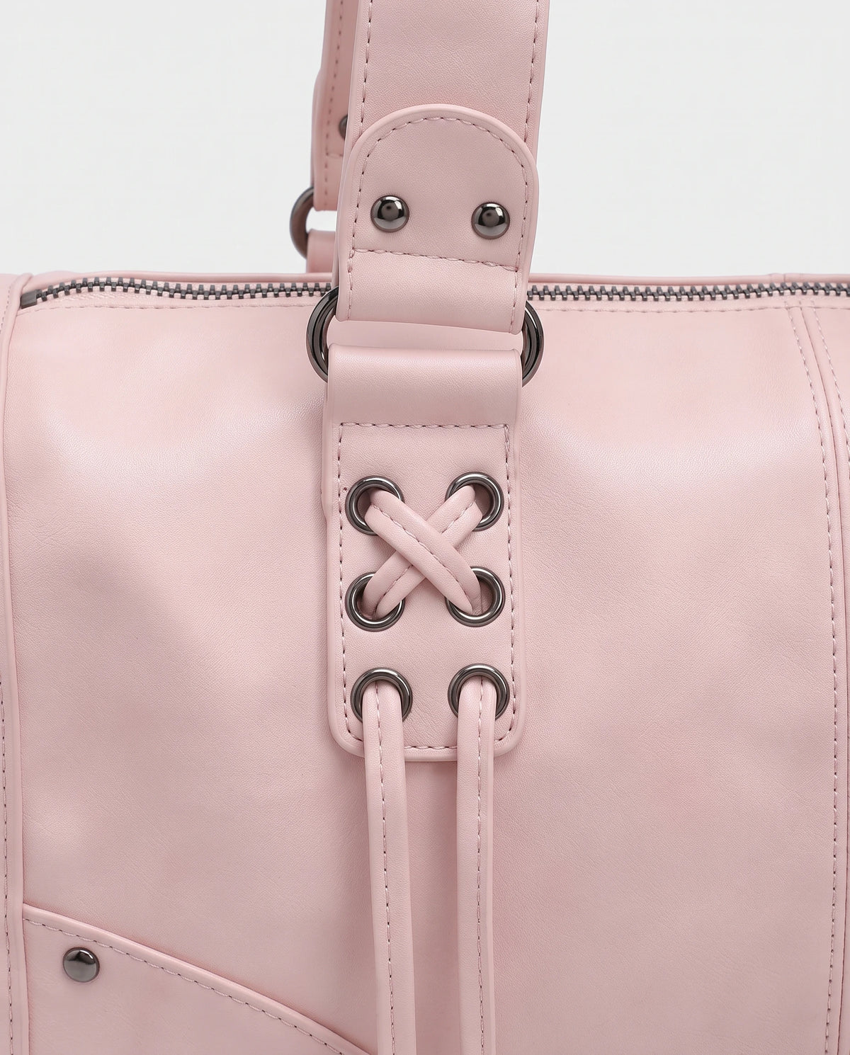 Grand sac à main bowling bandoulière style motard à lacets Avril coloris Rose Poudré, gros plan sur la patte à œillets lacée en croix, l'anneau et les clous argent foncé