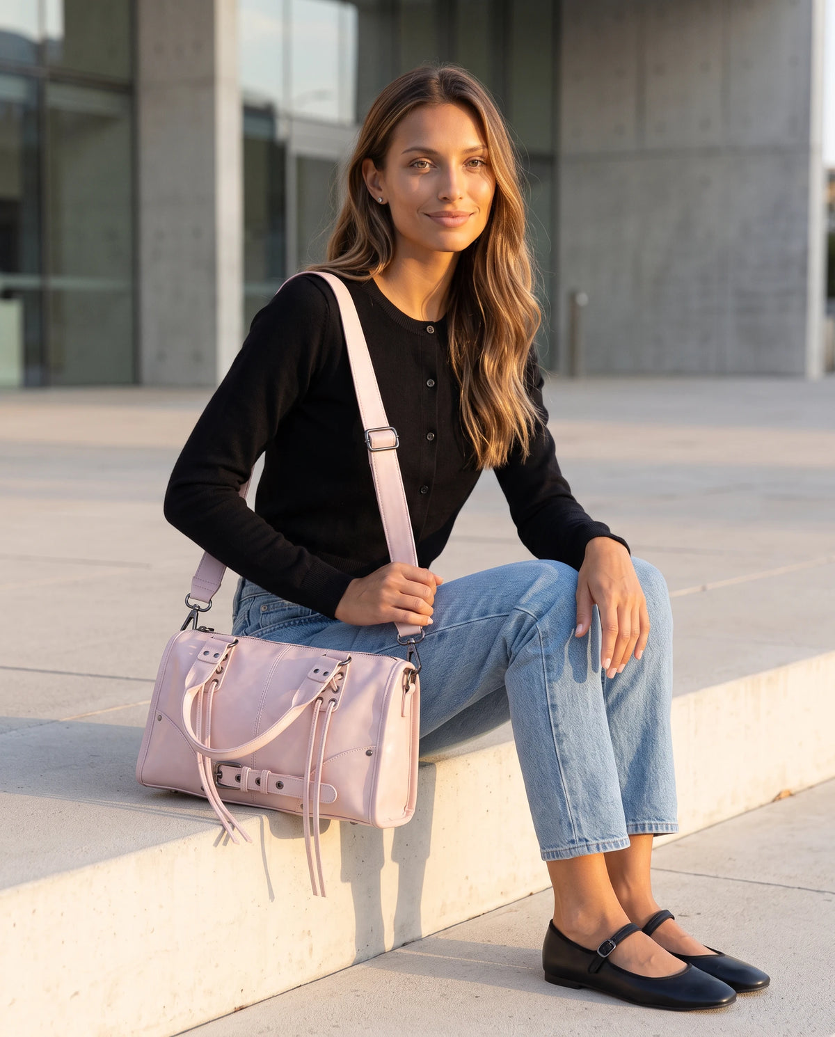 Grand sac à main bowling bandoulière style motard à lacets Avril coloris Rose Poudré, porté en bandoulière croisée, assise sur les marches d'un parvis de musée
