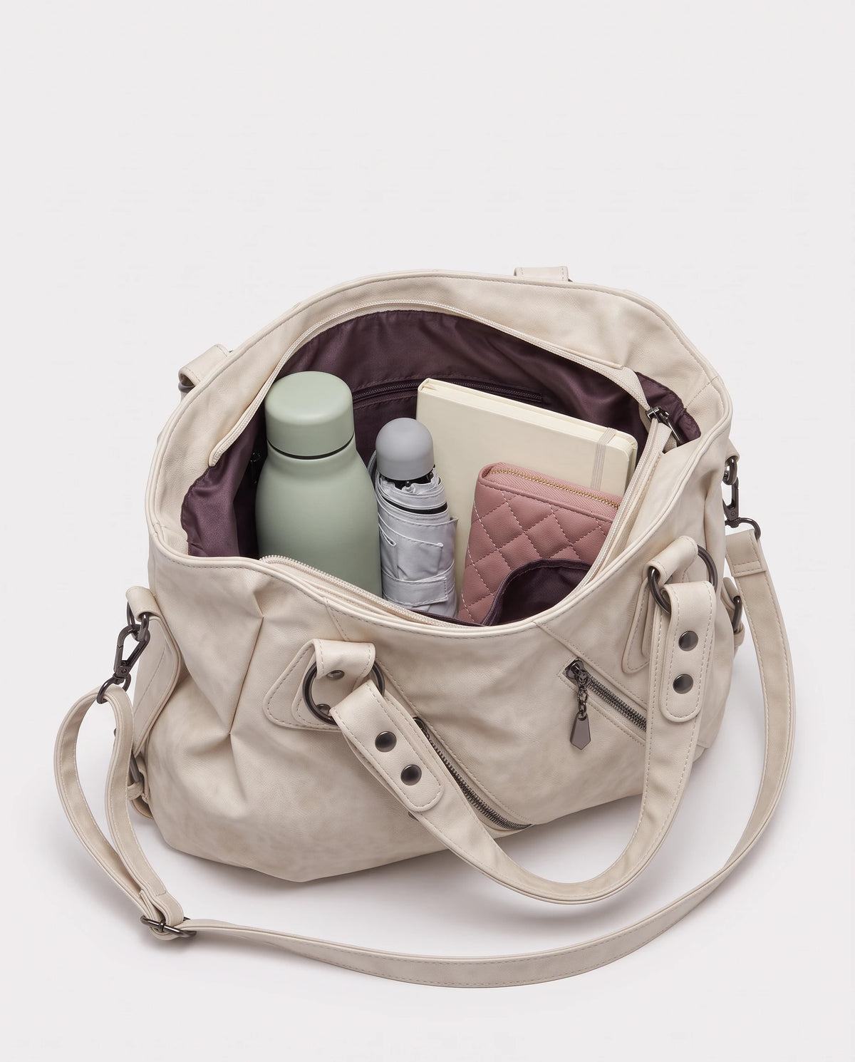 Grand sac à main hobo bandoulière style motard à zips Thelma coloris Blanc Cassé, intérieur rempli d'une gourde, d'un parapluie pliant, d'un portefeuille et d'un carnet