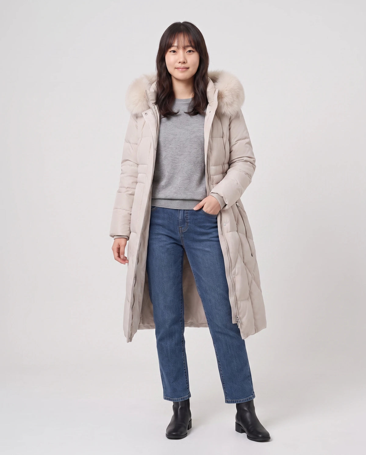 Lange taillierte Parka mit Kunstfellkapuze Noa in Beige, offen getragen über meliertem grauem Pullover