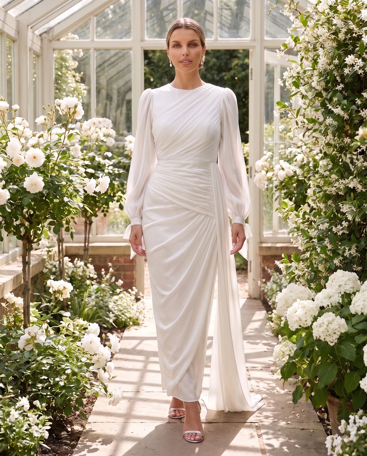 Robe longue plissée drapée à manches lanterne Élia en Blanc, portée dans une orangerie
