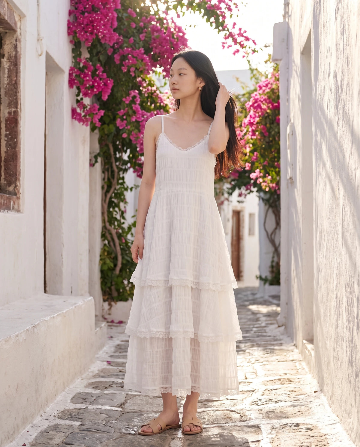 Robe longue à volants étagés et dentelle Elina en Blanc, portée dans une ruelle blanchie à la chaux