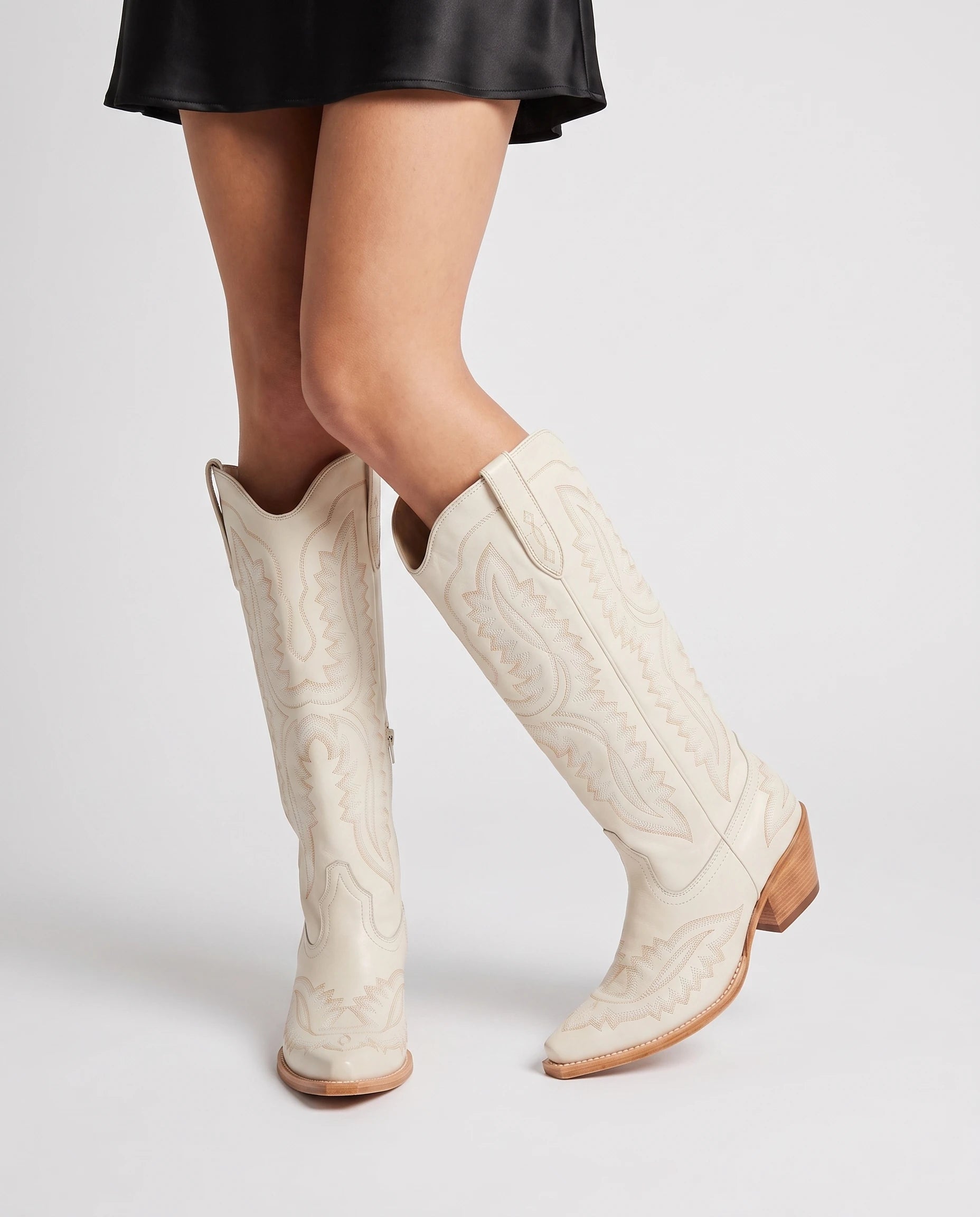 Bottes santiags hautes brodées effet cuir huilé Régine — Blanc Cassé, portées en plan rapproché