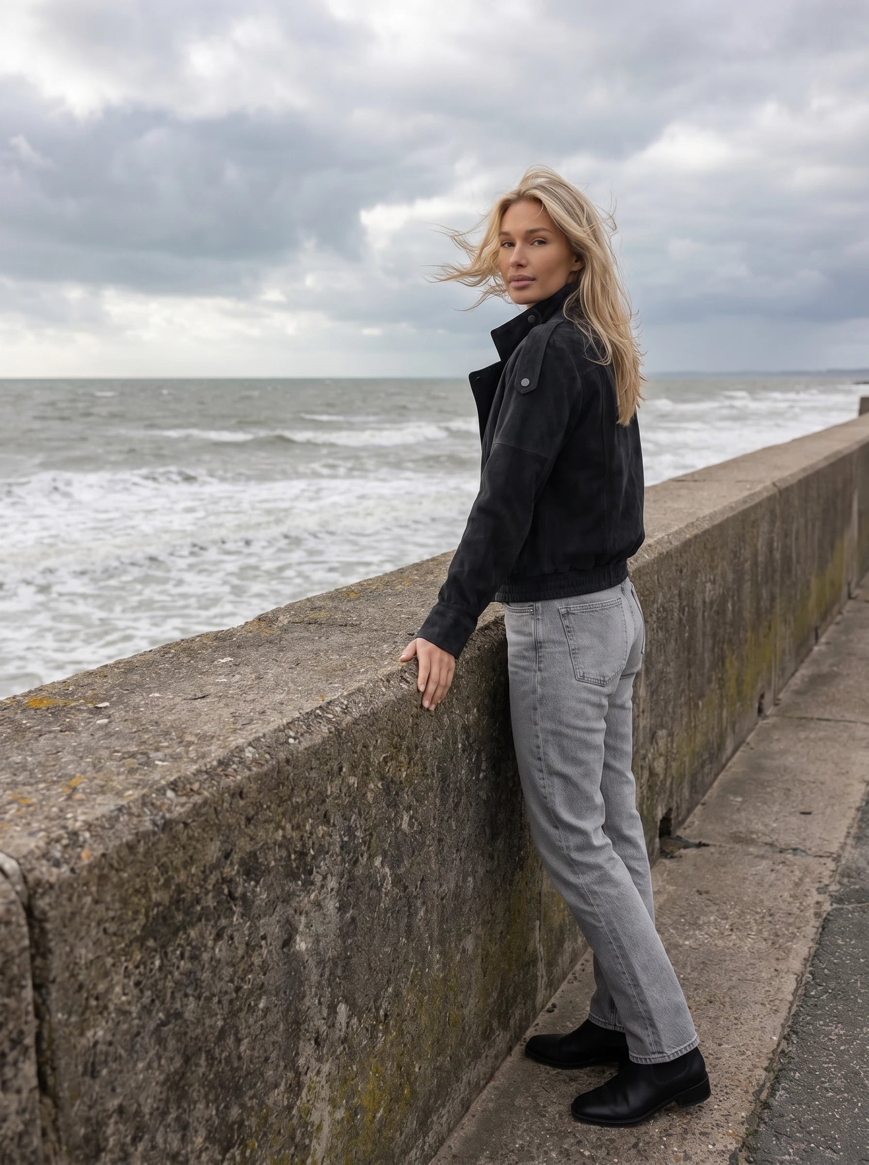 Veste biker en suédine noire Aldegonde, portée face à la mer par temps venteux