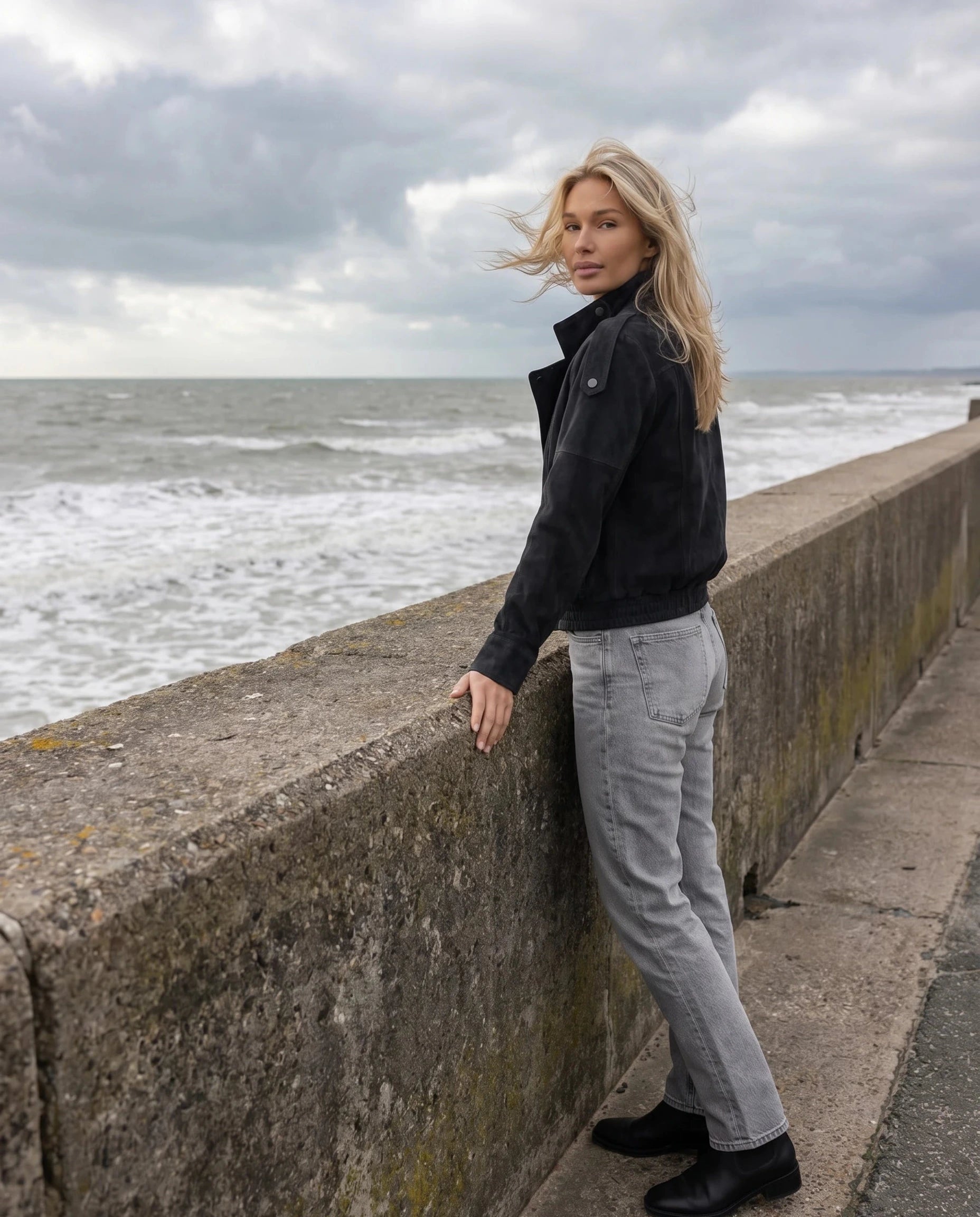 Veste biker en suédine noire Aldegonde, portée face à la mer par temps venteux